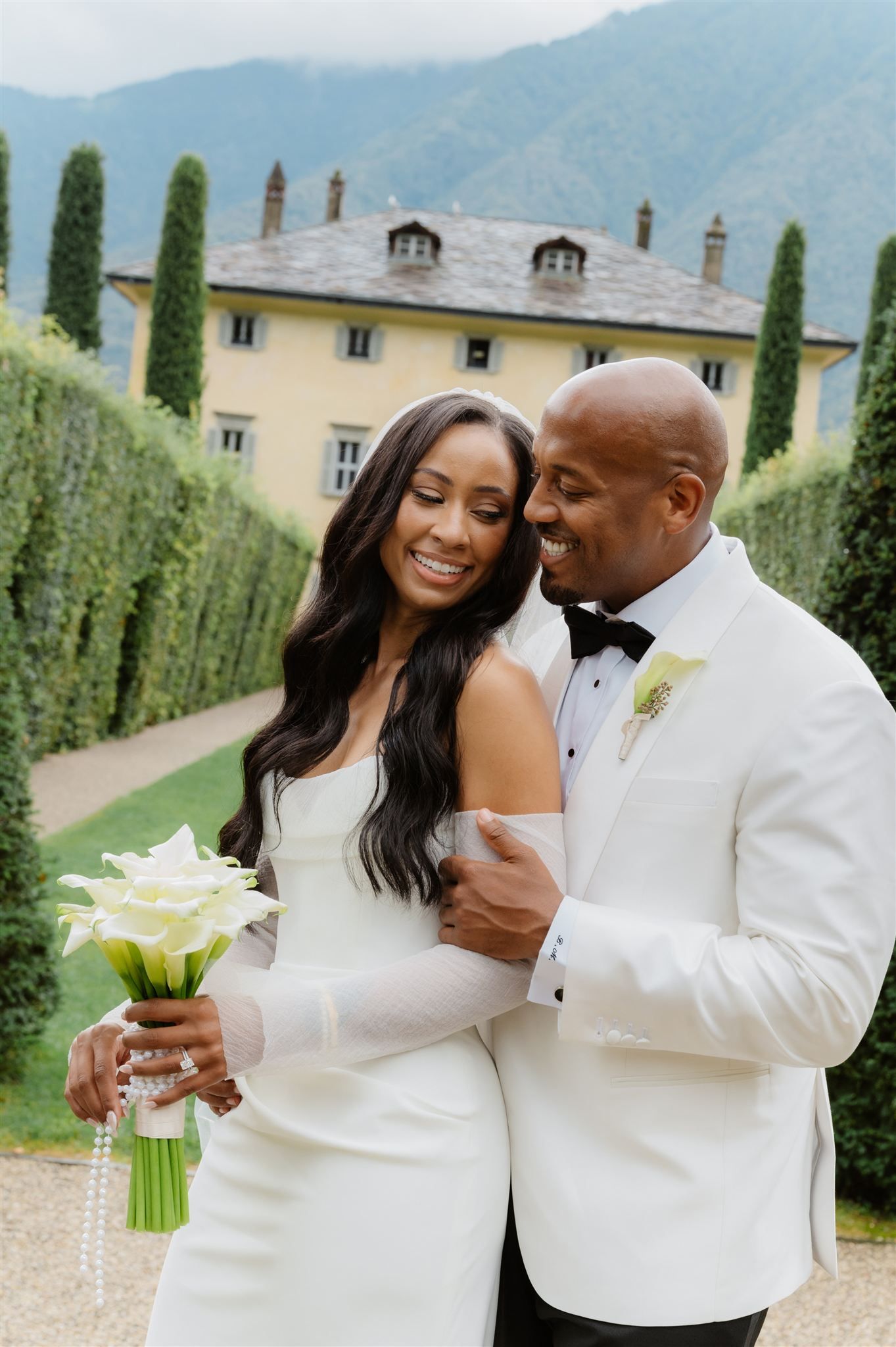 Romantic wedding couple shares intimate moments in front of Italian villa with cypress trees.
