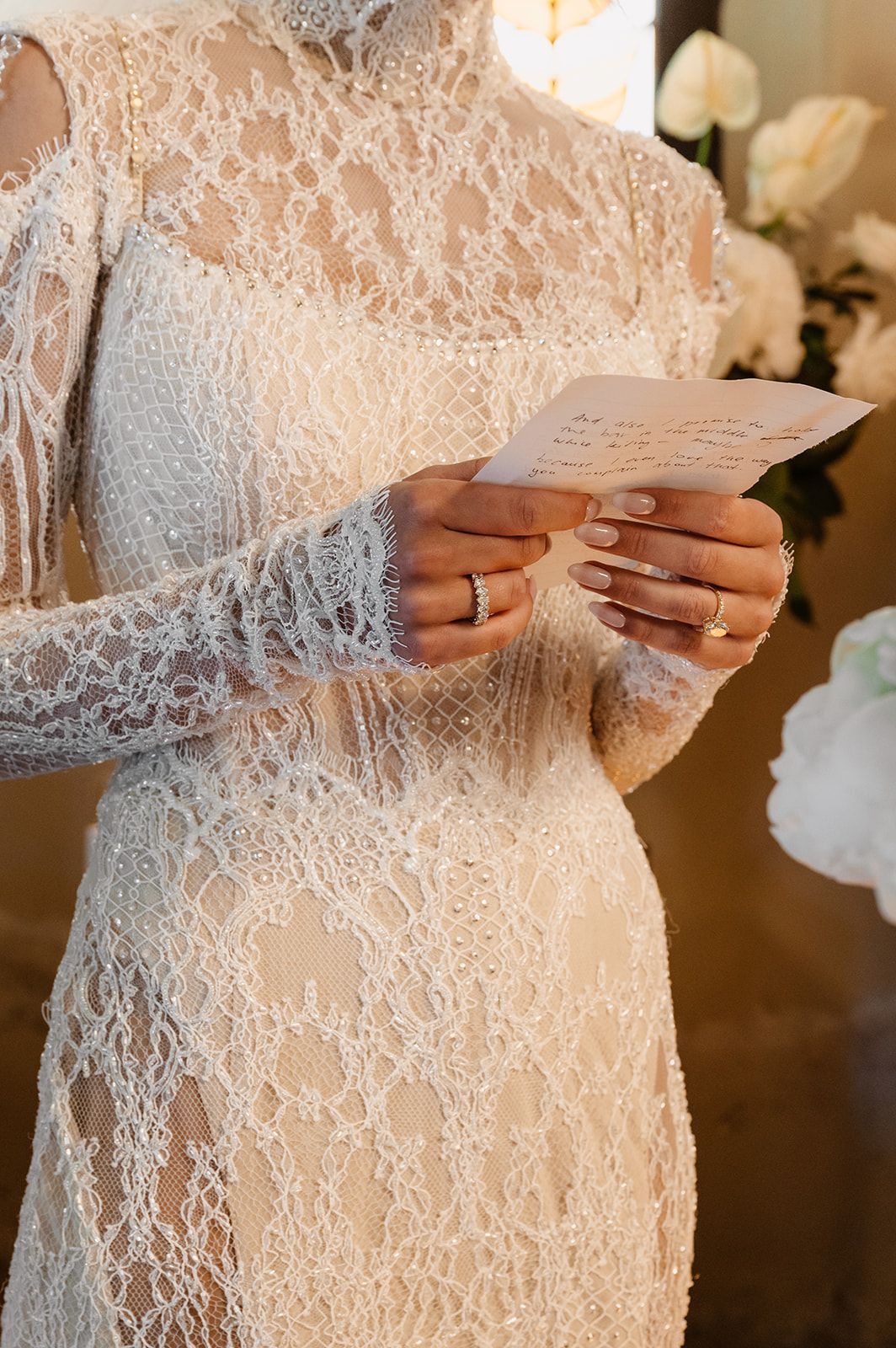 Detail shot of intricate lace wedding dress with delicate beading and long sleeves.