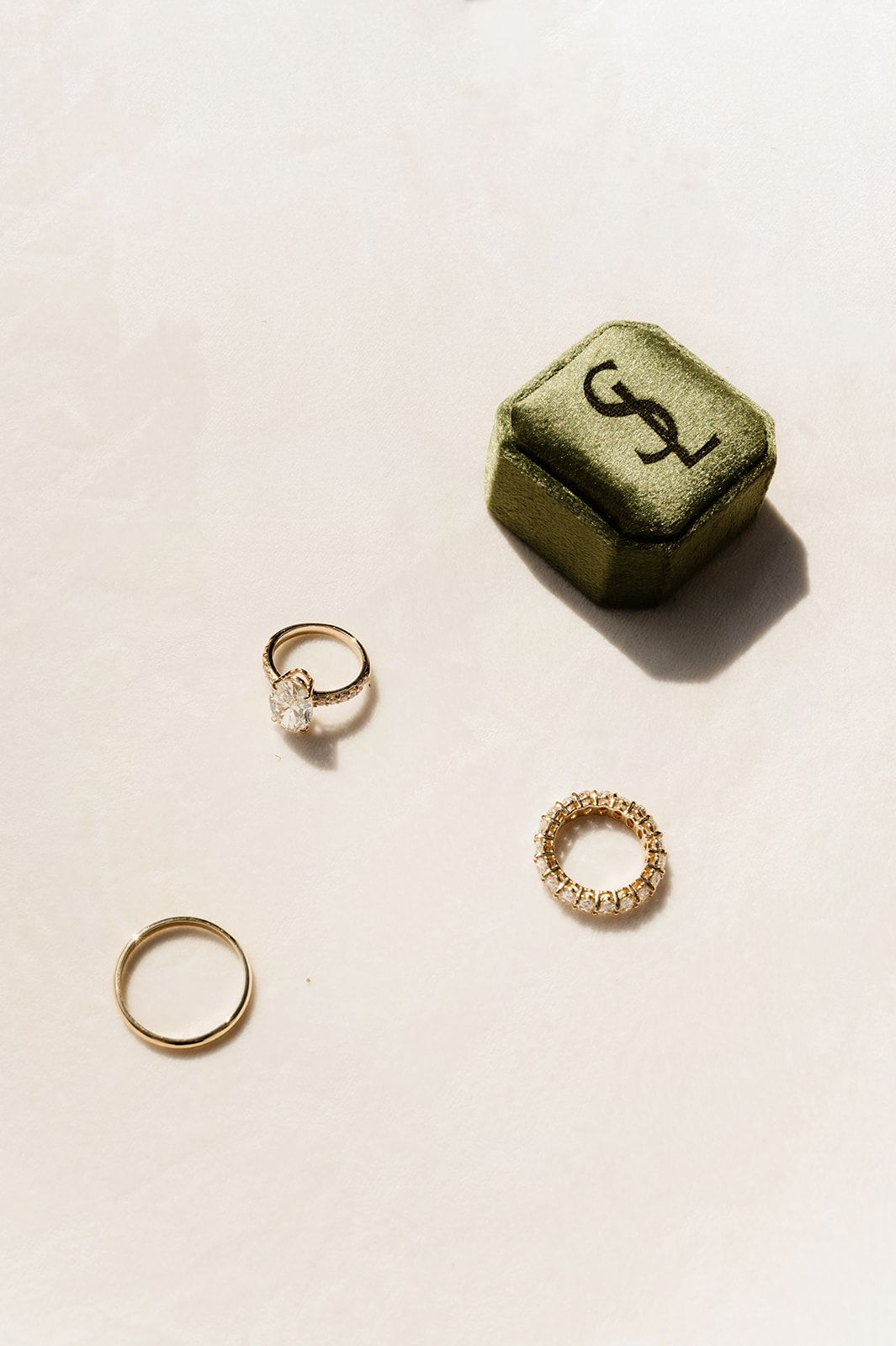 Gold wedding rings and jewelry arranged on a white surface.