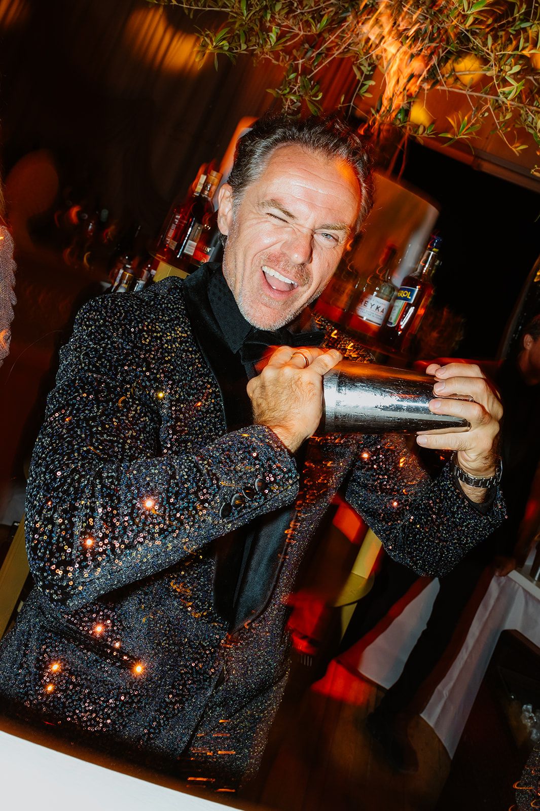 DJ performing energetically in a sparkly dark outfit at a wedding reception.