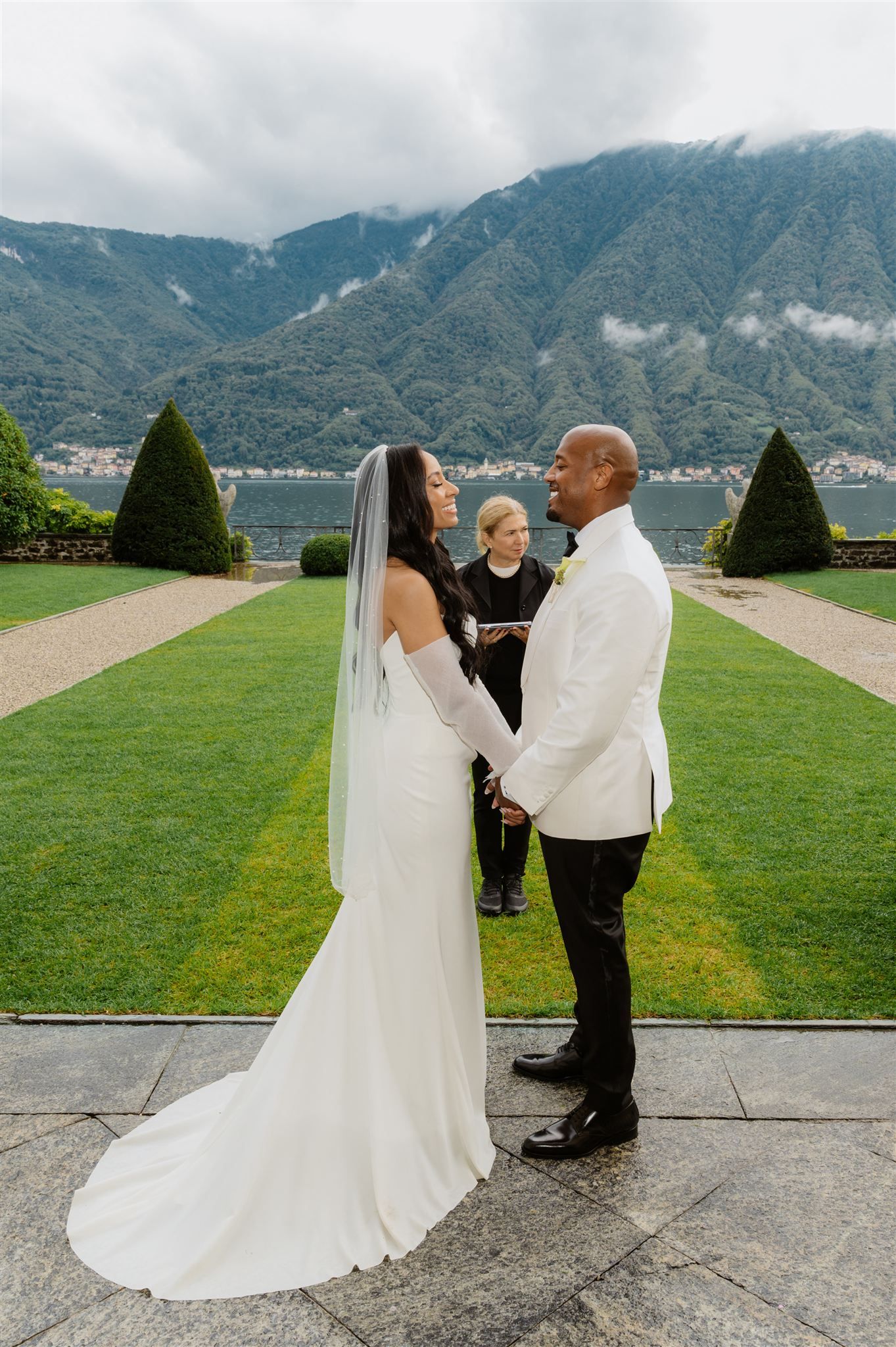 A wedding couple shares a romantic moment on a scenic terrace overlooking mountain landscapes.