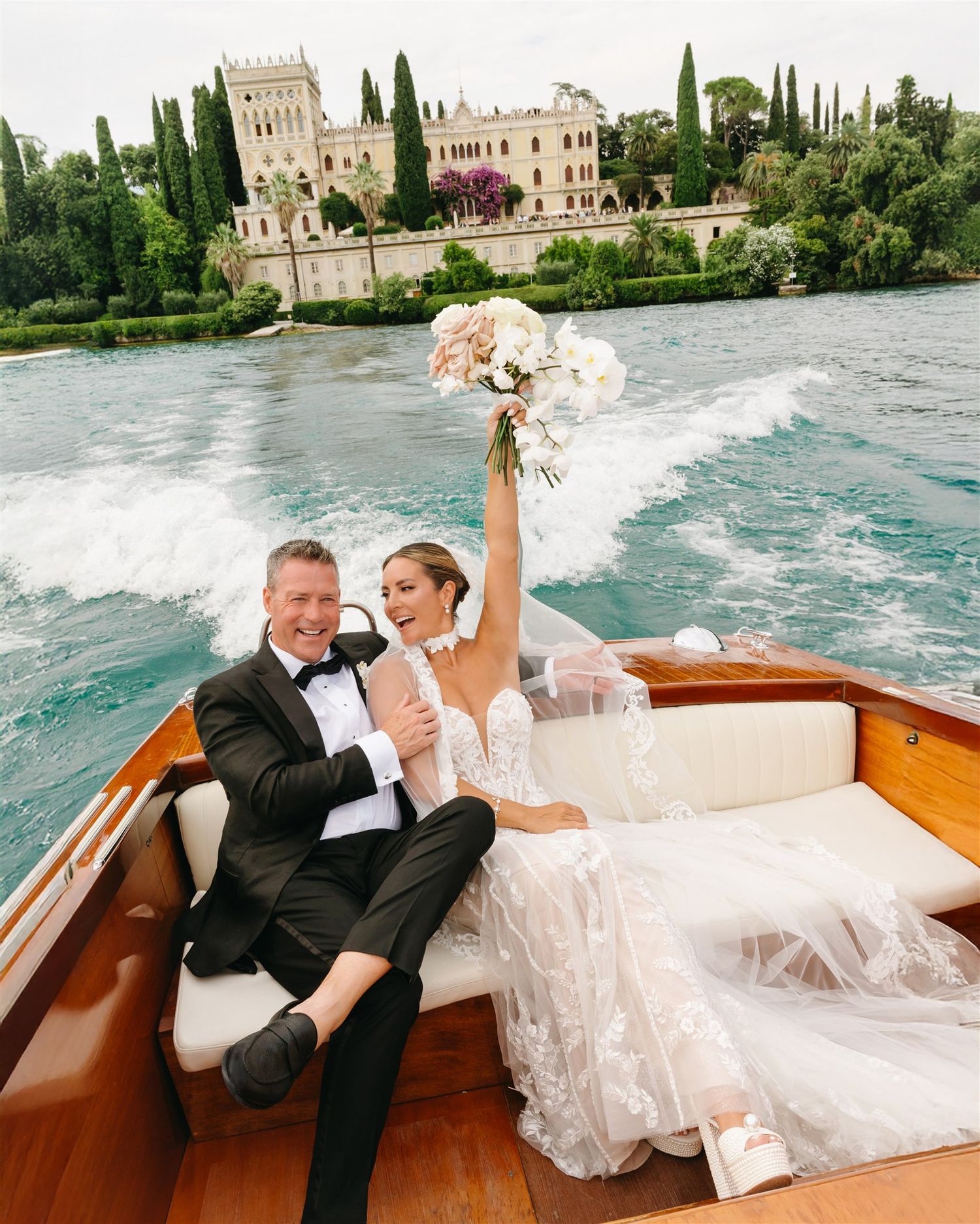 A couple enjoys a romantic boat ride on Lake Garda with a historic Italian villa in the background.