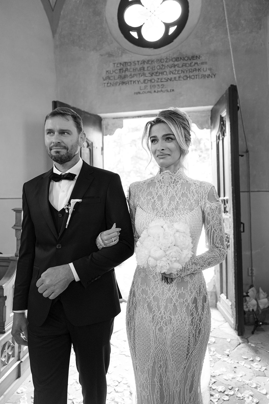 Wedding couple in classic black and white attire standing in a church with gothic architecture.