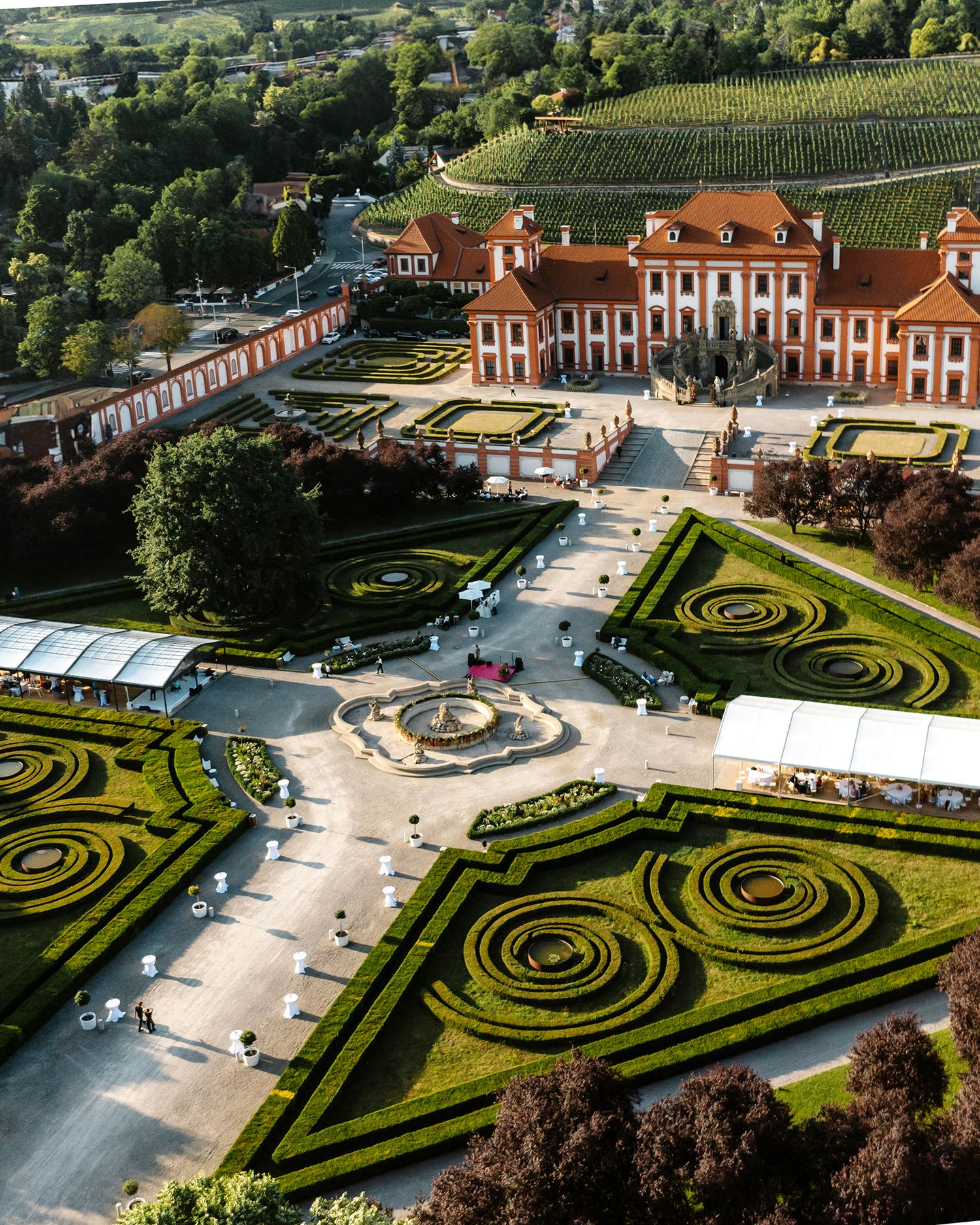 Drone shot of a luxury venue featuring symmetrical spiral gardens and classical architecture. European wedding.