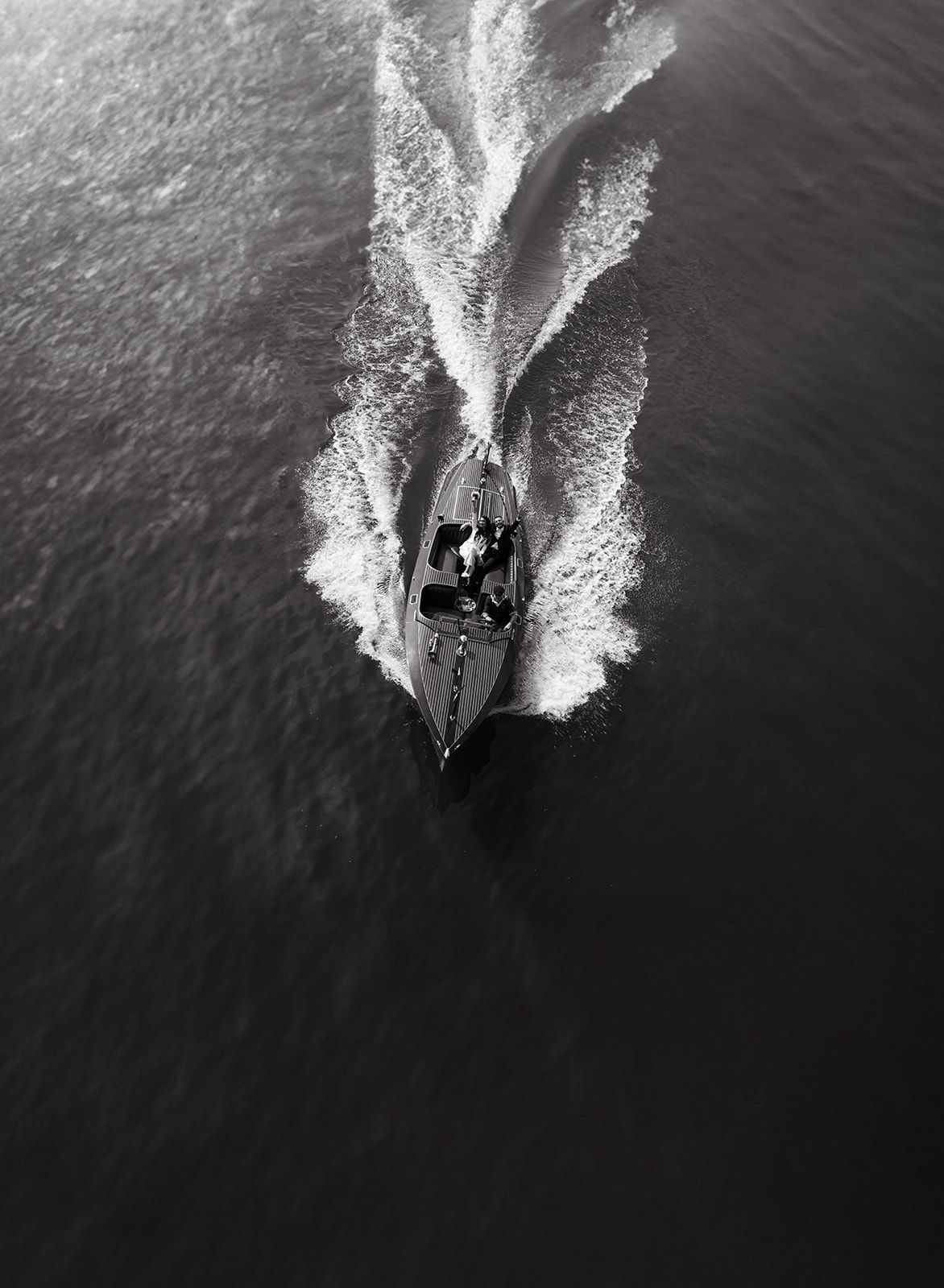 Dramatic aerial shot of a boat's wake pattern in black and white photography on dark waters in Paris.