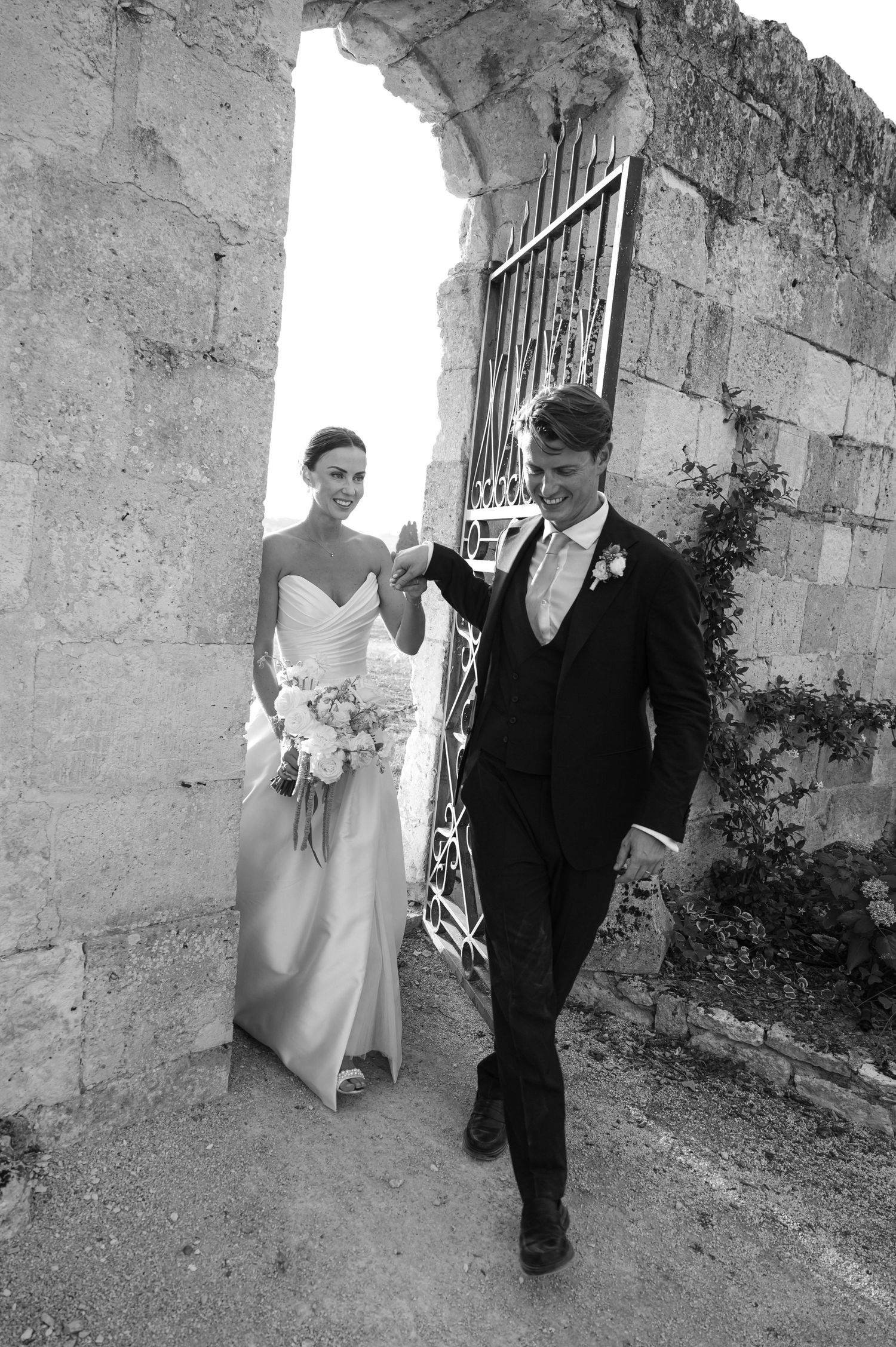 A black and white sequence shows a couple walking through stone archways at their wedding.