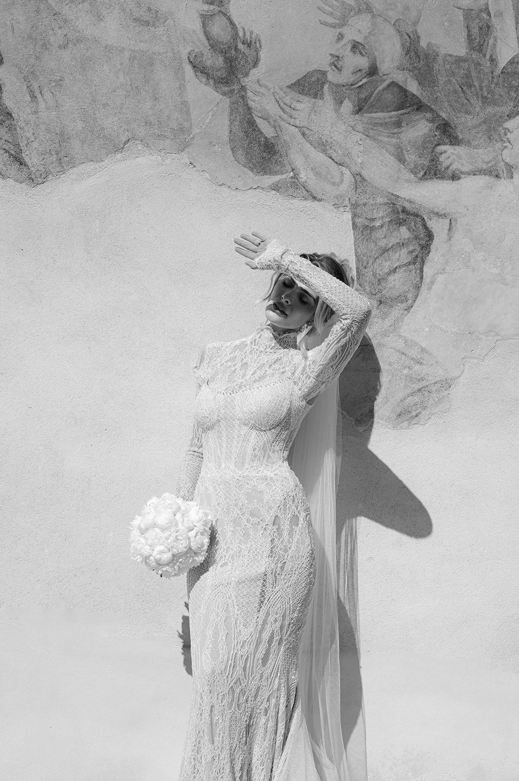 Black and white artistic photo of wedding dress details with dramatic lighting and shadows.