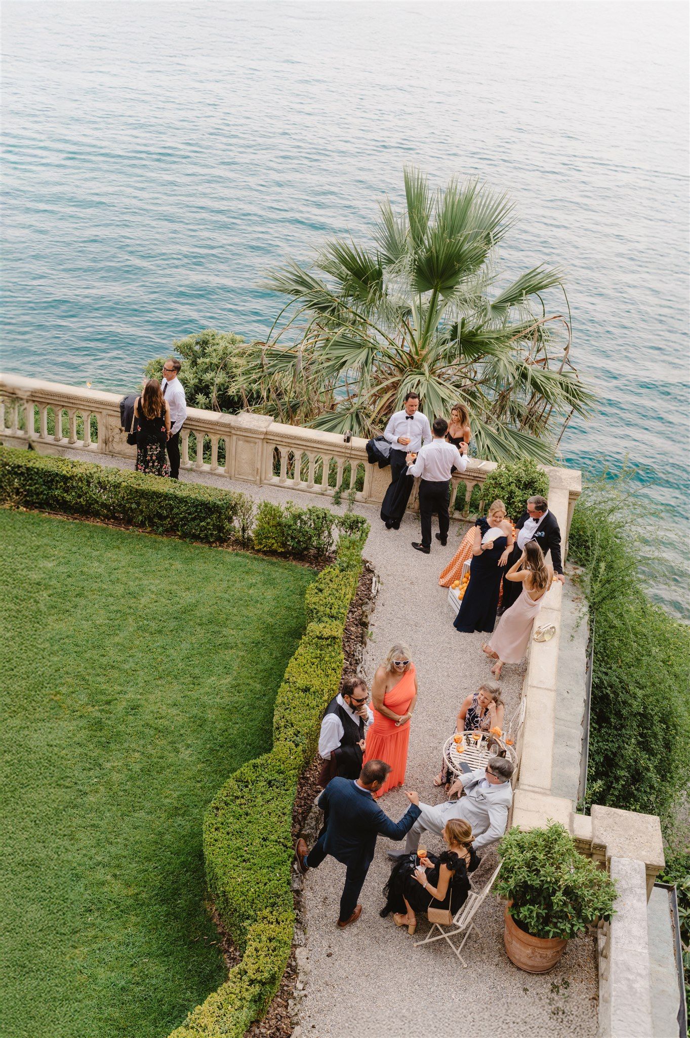 Wedding reception guests gathered on a coastal terrace overlooking the Mediterranean Sea.