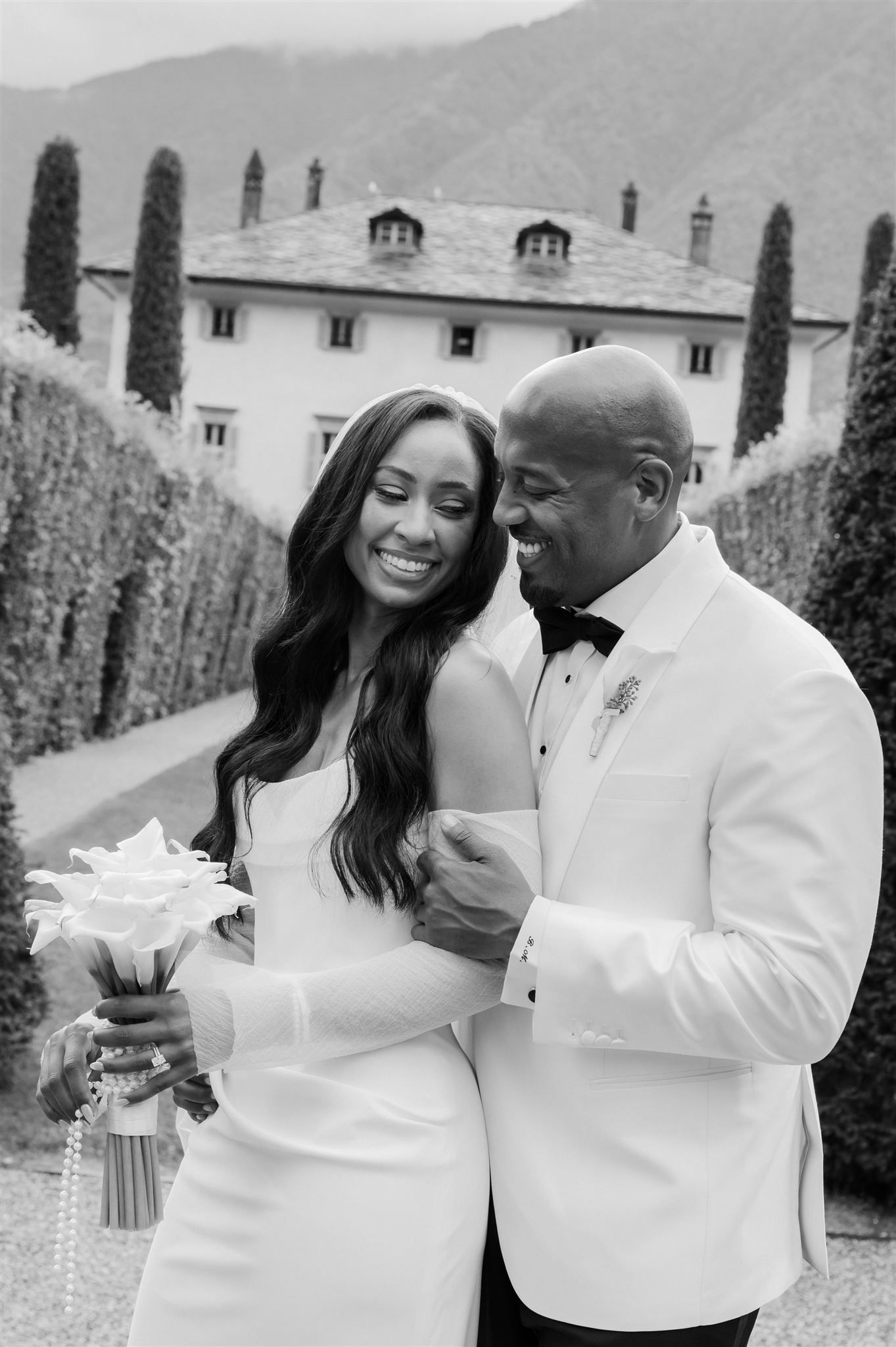 Happy couple sharing joyful moment in elegant garden setting during wedding celebration.