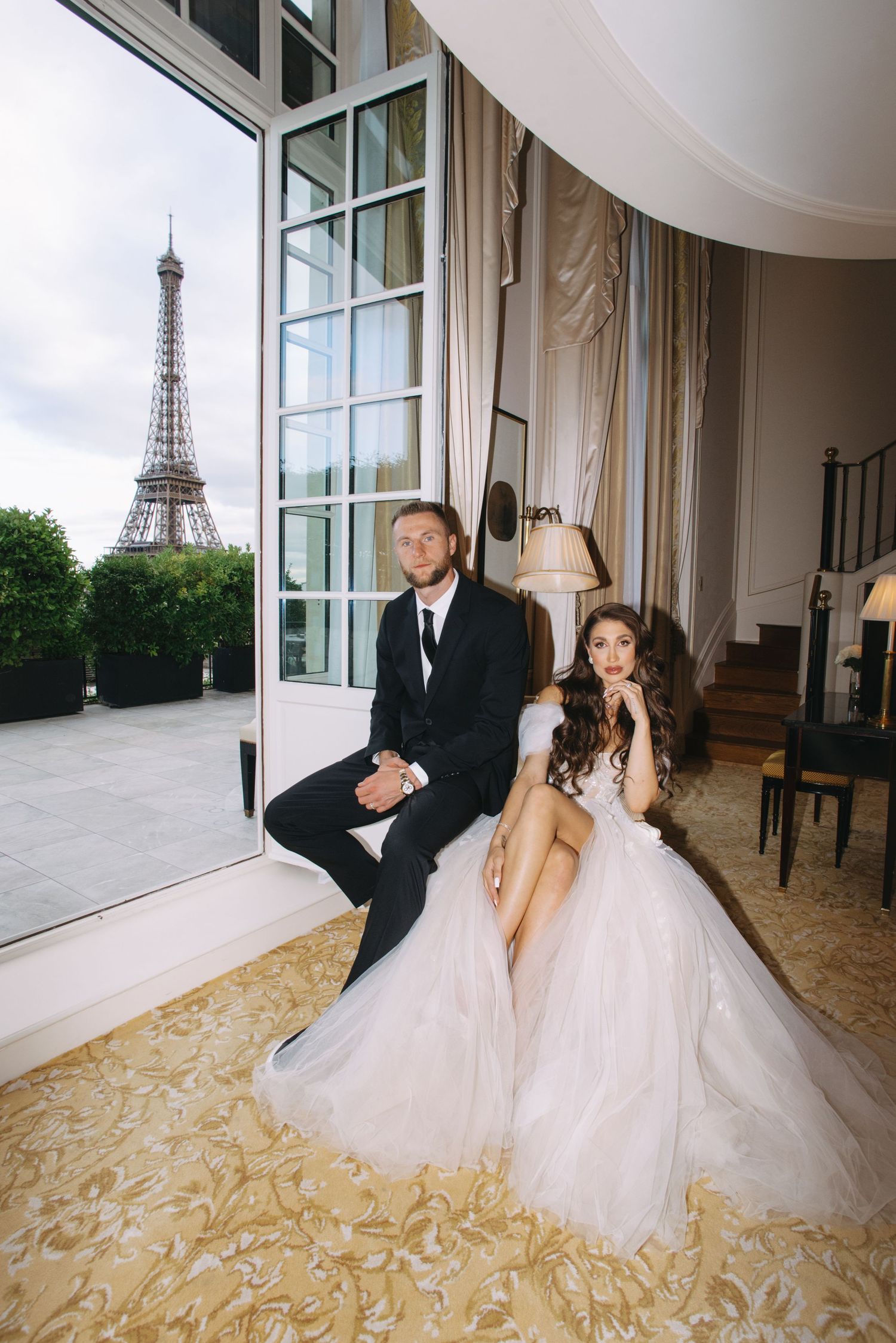 A romantic wedding photoshoot in Paris with the Eiffel Tower visible through elegant windows.