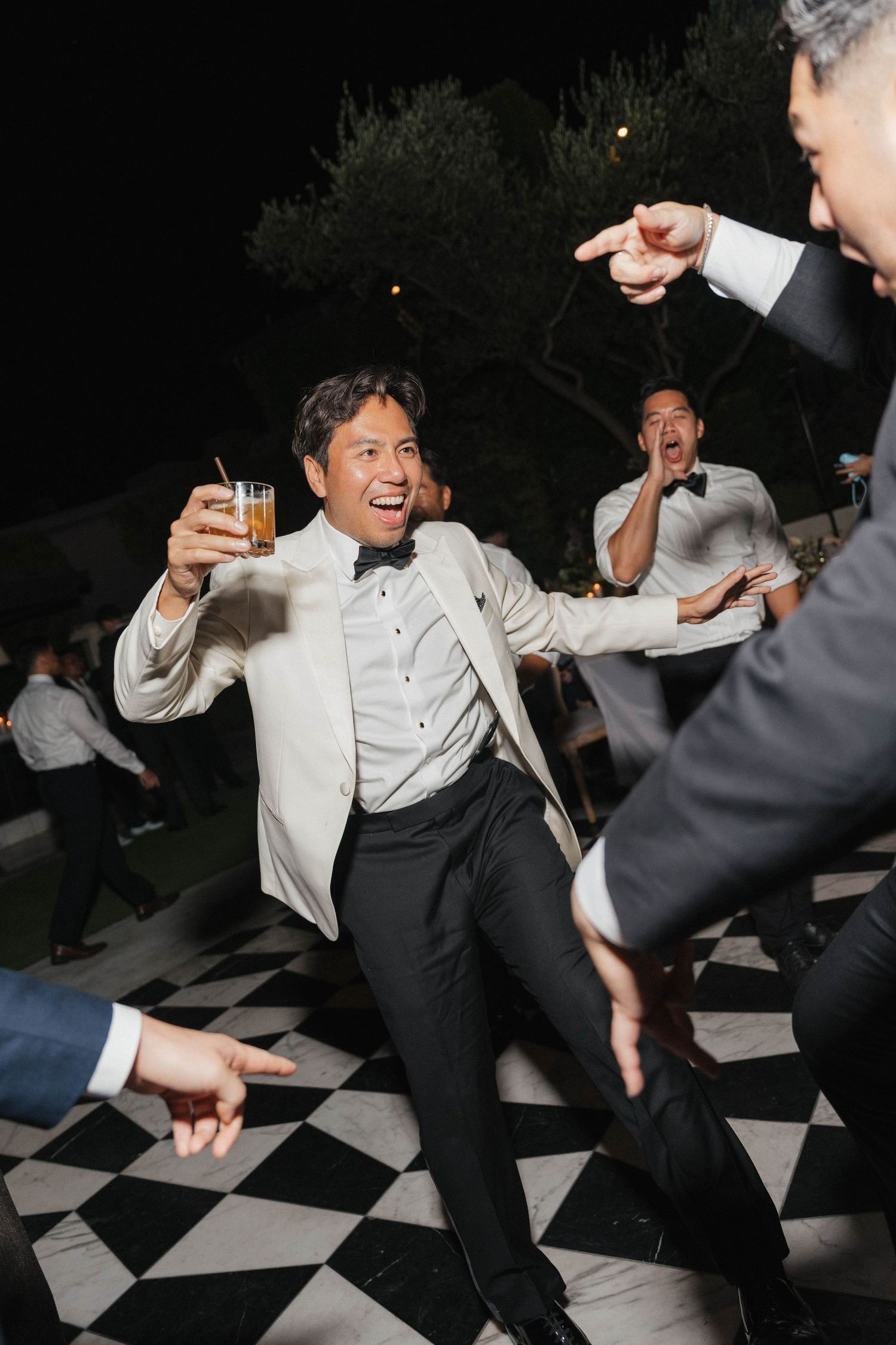 Wedding guest dancing energetically on black and white checkered dance floor.