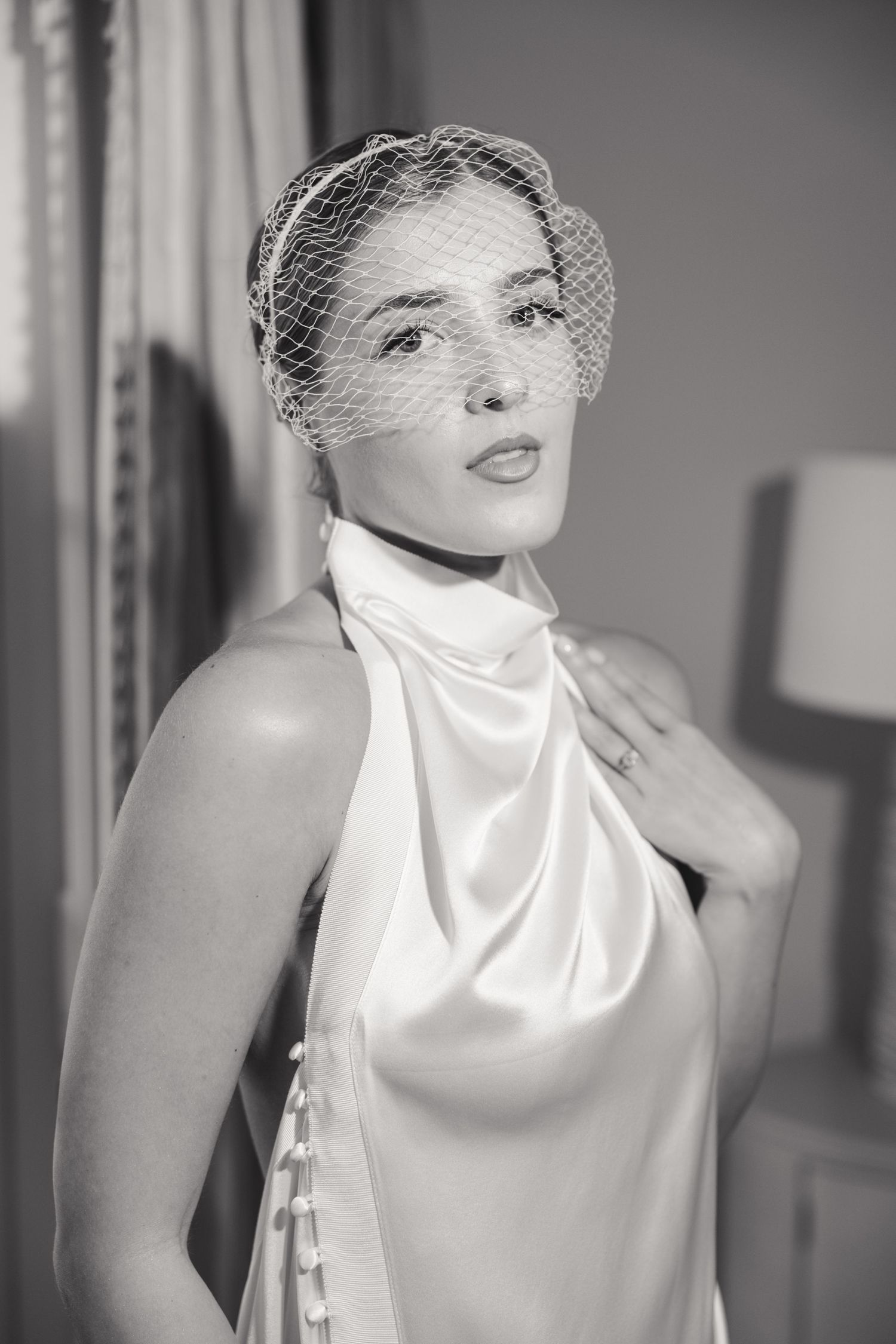Black and white fashion portrait featuring a sleek white turtleneck and delicate mesh veil.