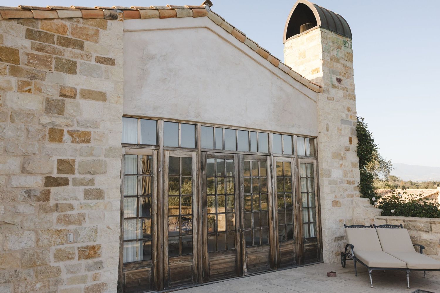 Series of glass windows and doors along a limestone building exterior with architectural details.