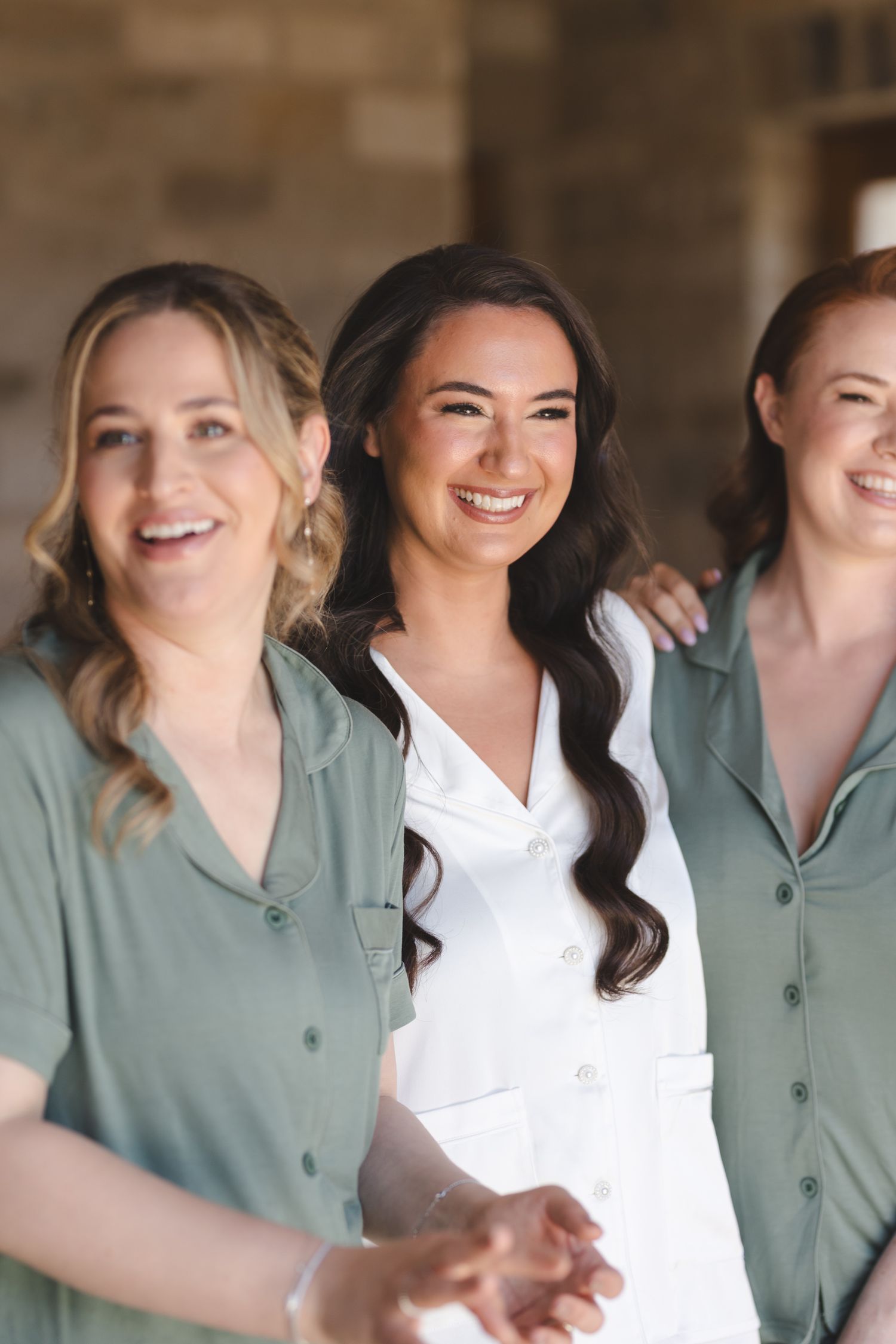 Wedding party members sharing joyful moments in sage green and white attire.