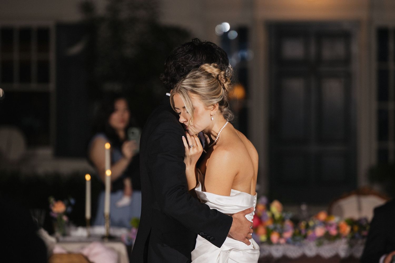 A wedding reception venue at night with elegant table settings and soft lighting.