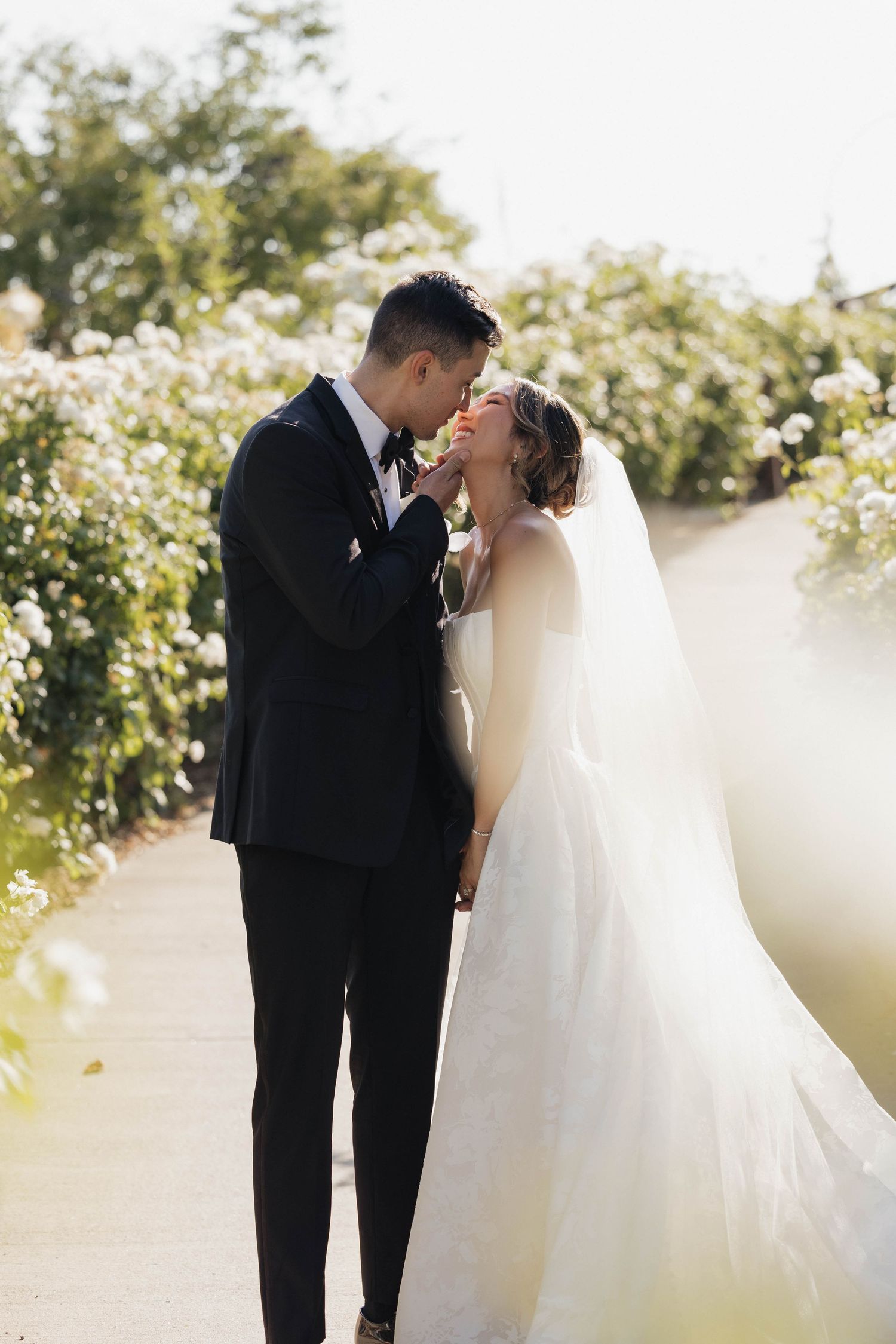Romantic wedding couple sharing an intimate moment in a sunlit garden setting.