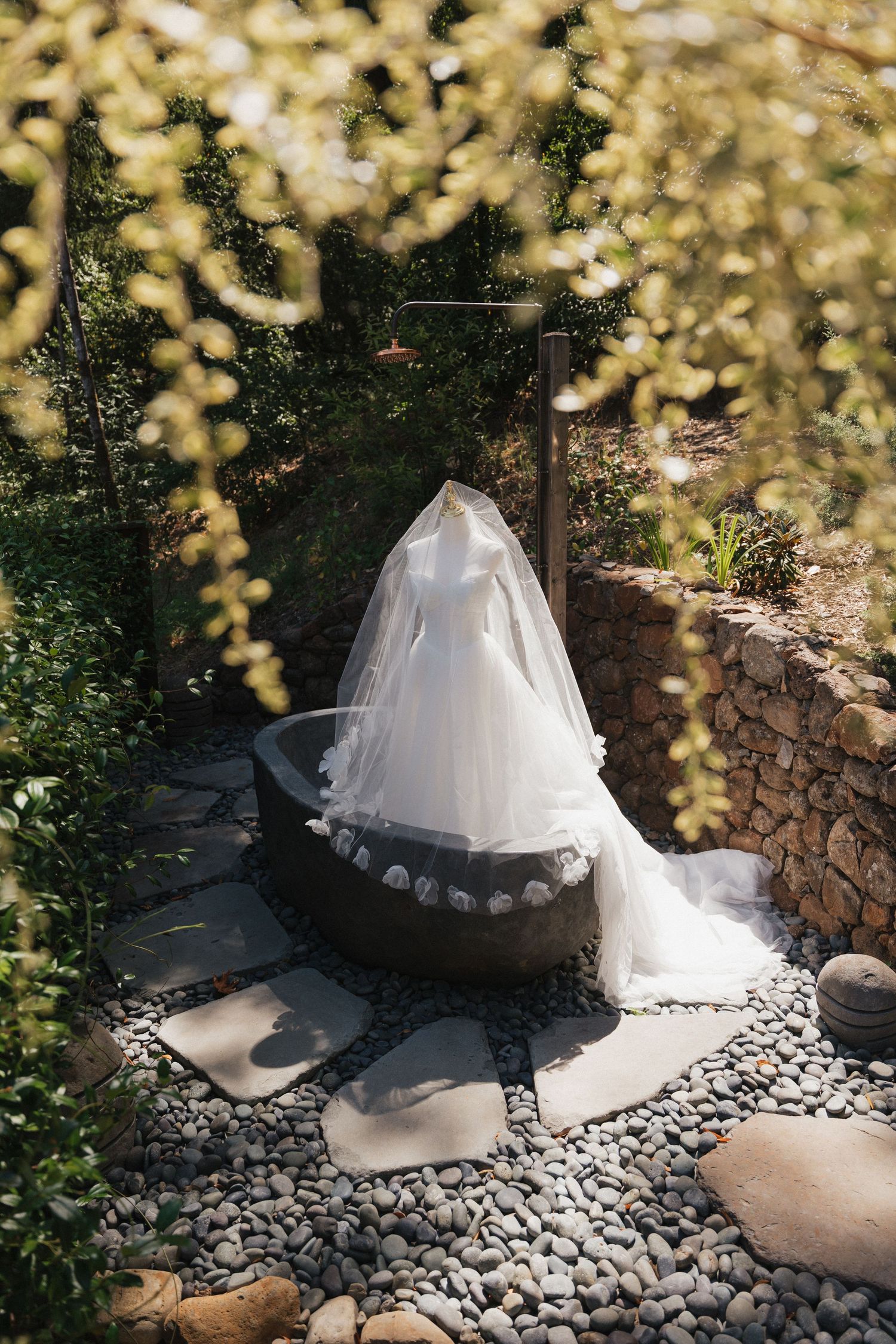 White tent structure with stone border decorations in a garden setting.