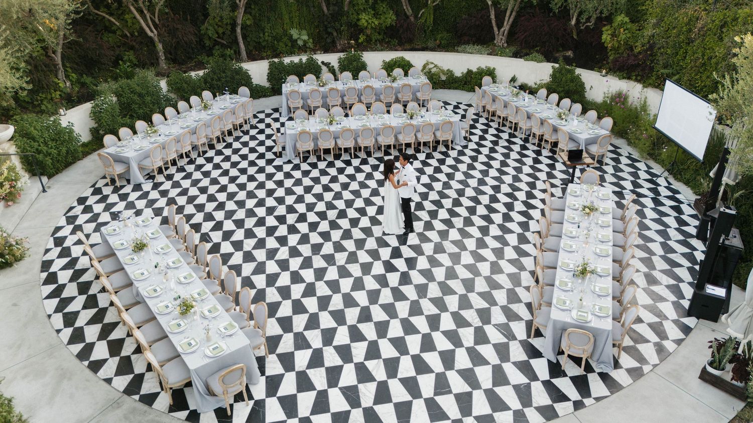 Aerial view of black and white checkered outdoor wedding ceremony setup.