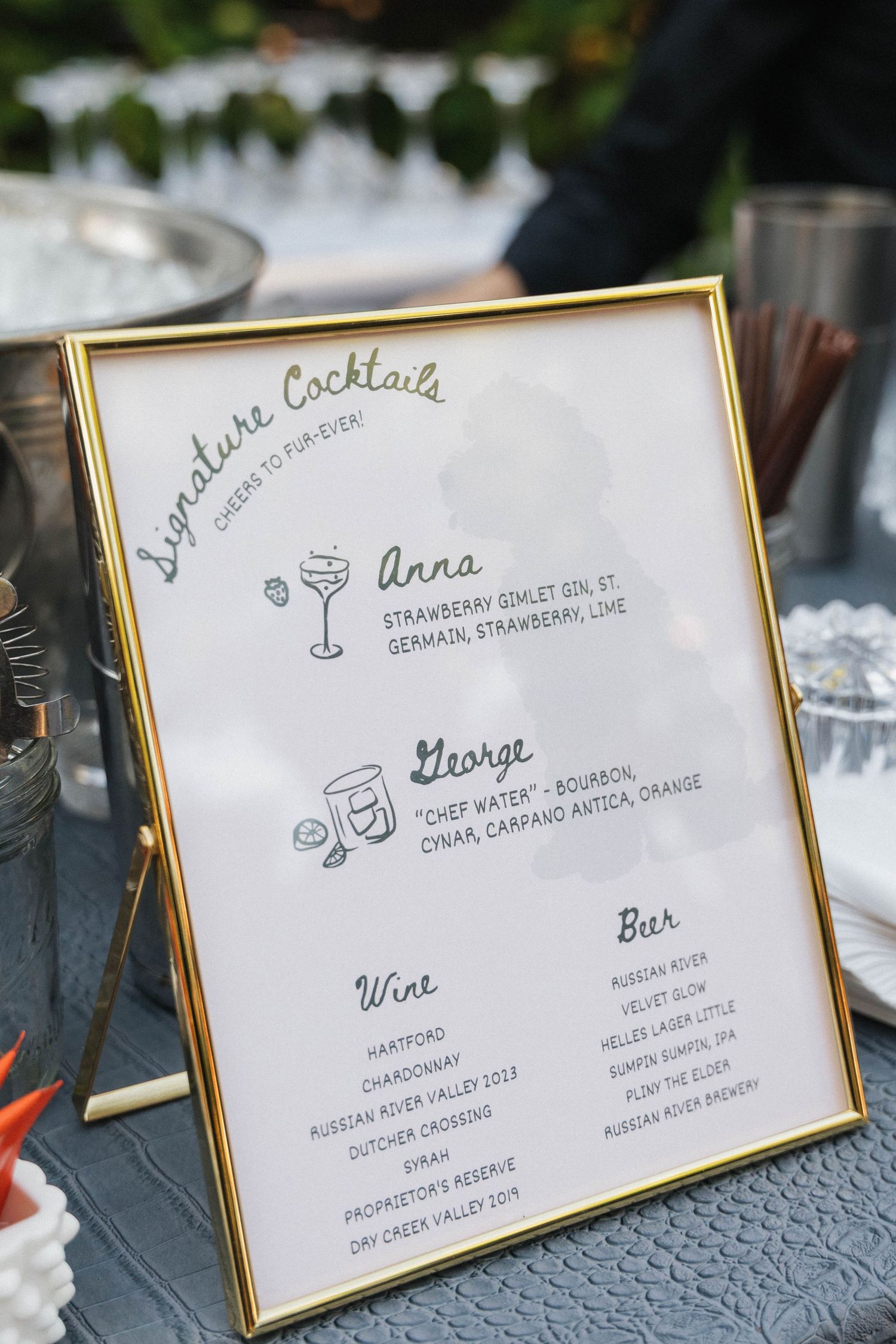 A framed wedding cocktail menu displays signature drinks and wine selections.