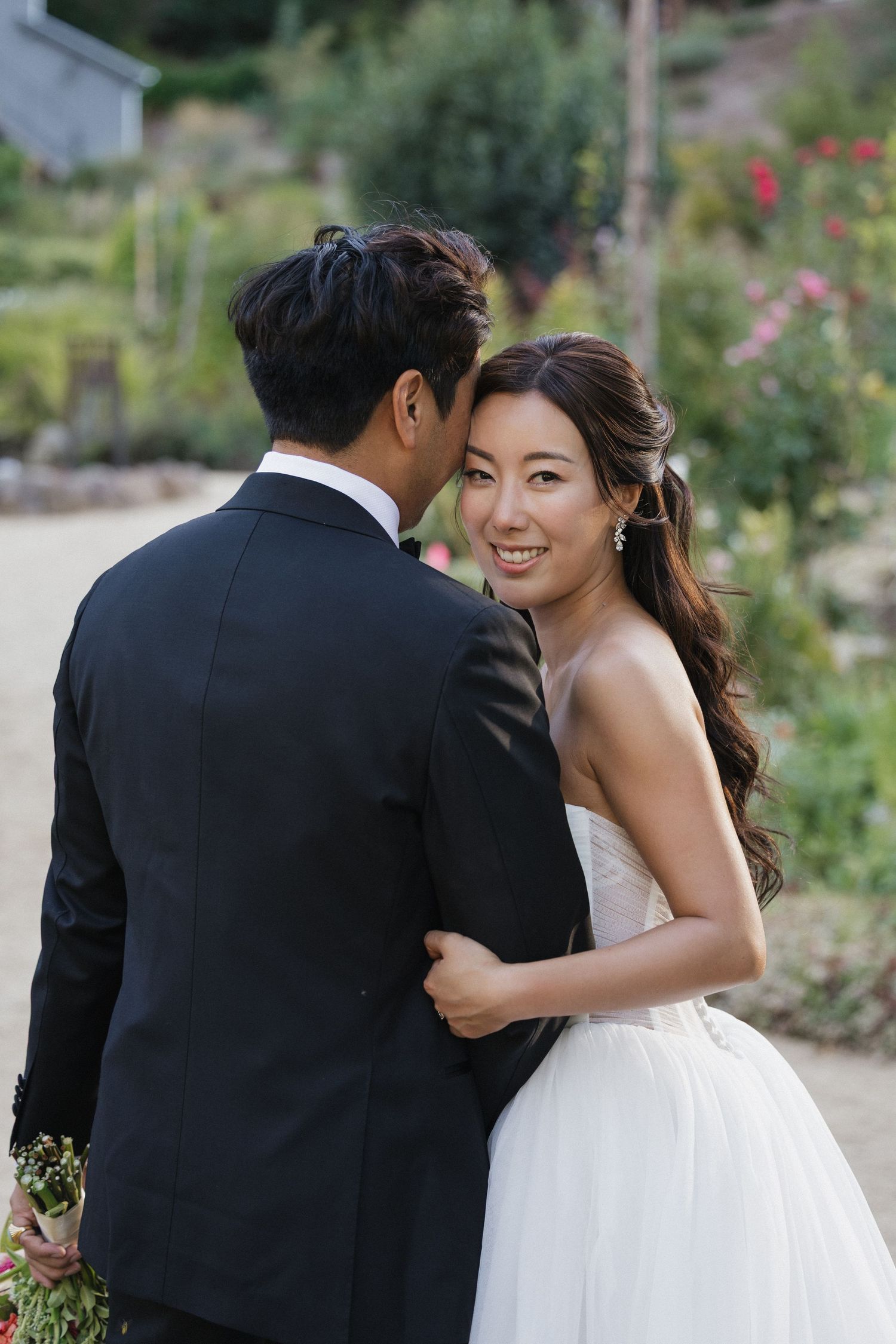 Couple shares intimate moment in garden setting during wedding photoshoot.
