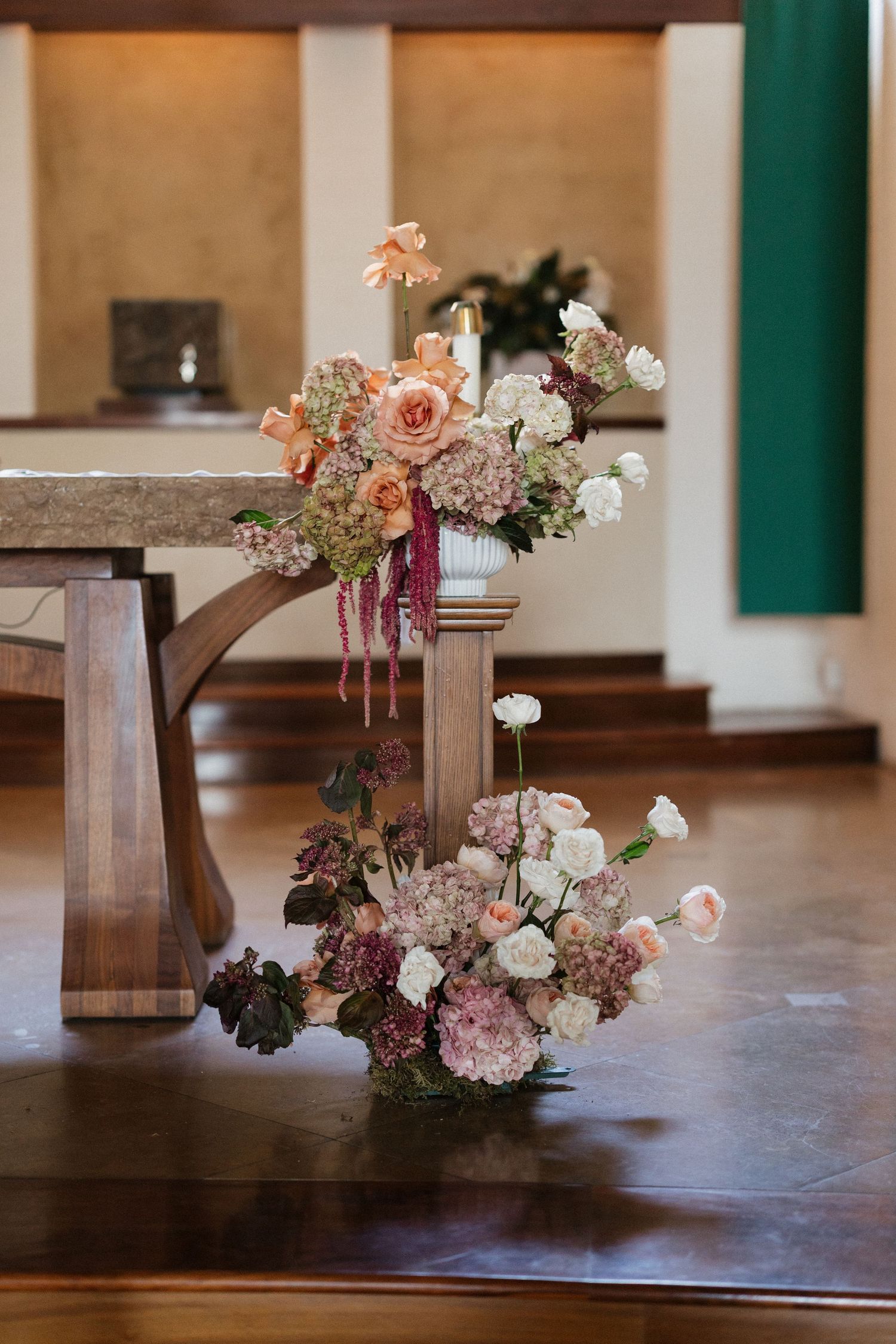 Elegant peach and blush floral arrangements decorating church altar for wedding ceremony.