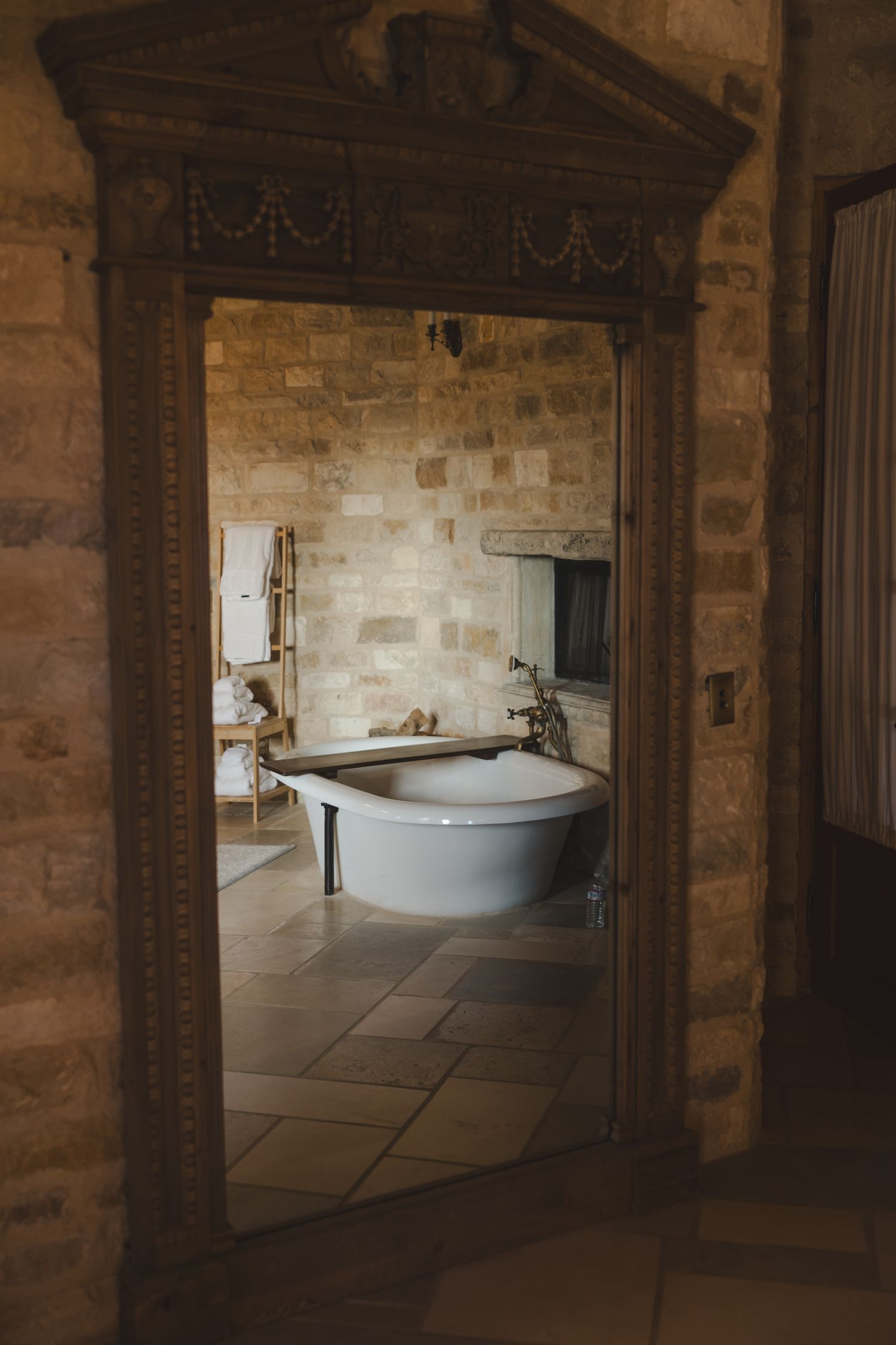 Stone-walled interior hallway with arched doorways and a freestanding bathtub visible through the entrance.