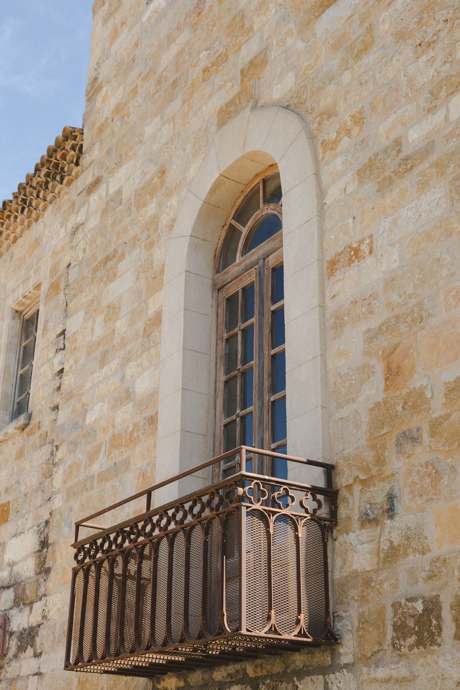Historic stone building exterior with ornate wrought iron balconies and arched windows.