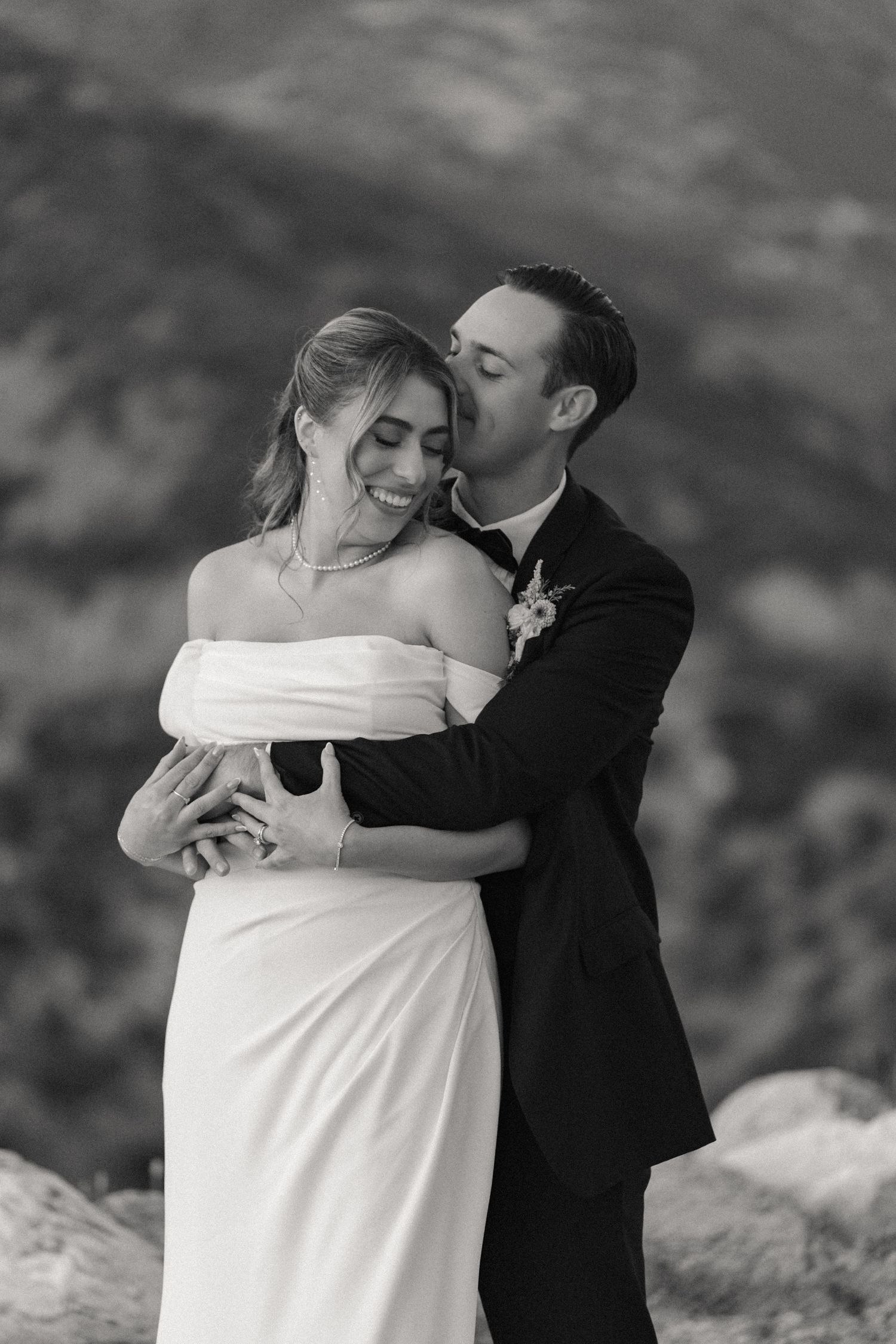 An intimate black and white portrait of a couple embracing in their wedding attire.