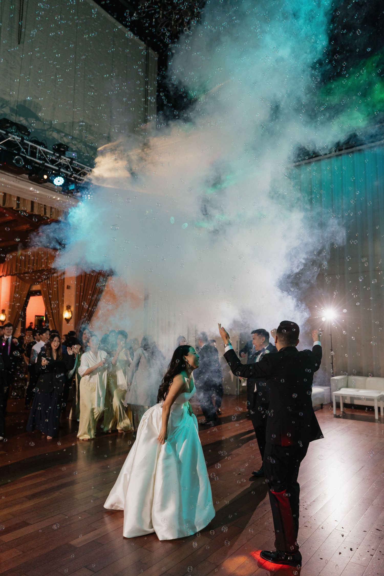 Bride and groom share first dance surrounded by colorful smoke effects and sparklers at elegant wedding reception.