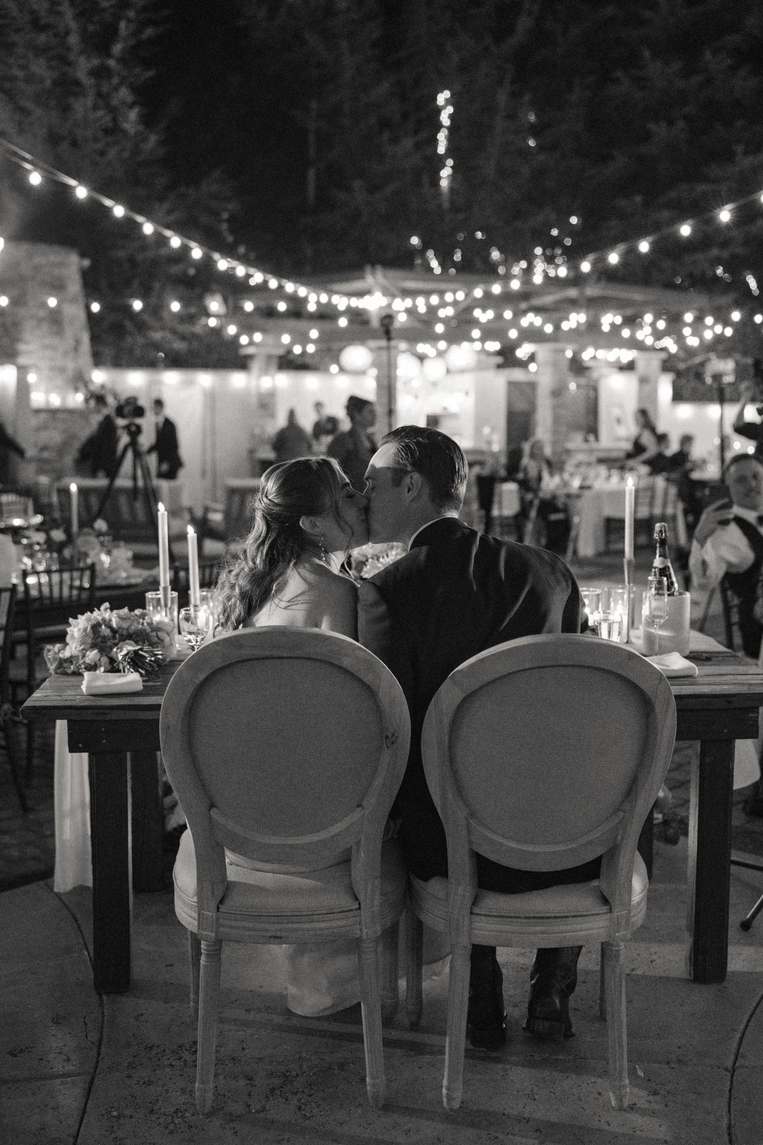 Reception setup with elegant chairs and string lights creating romantic ambiance at night.