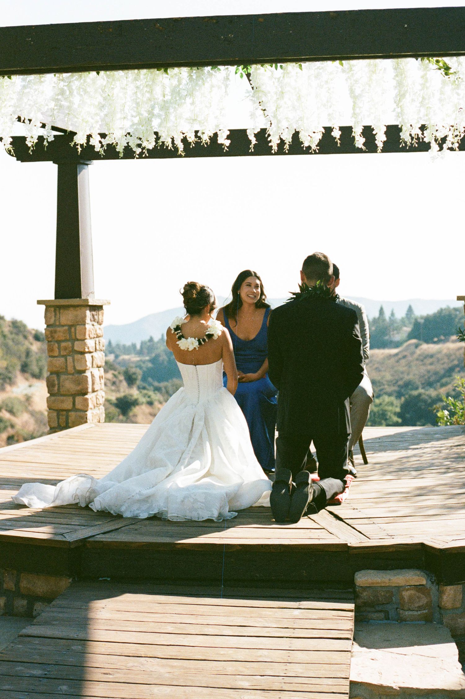 Wedding ceremony on an outdoor deck overlooking mountain views with floral decorations and white draping.