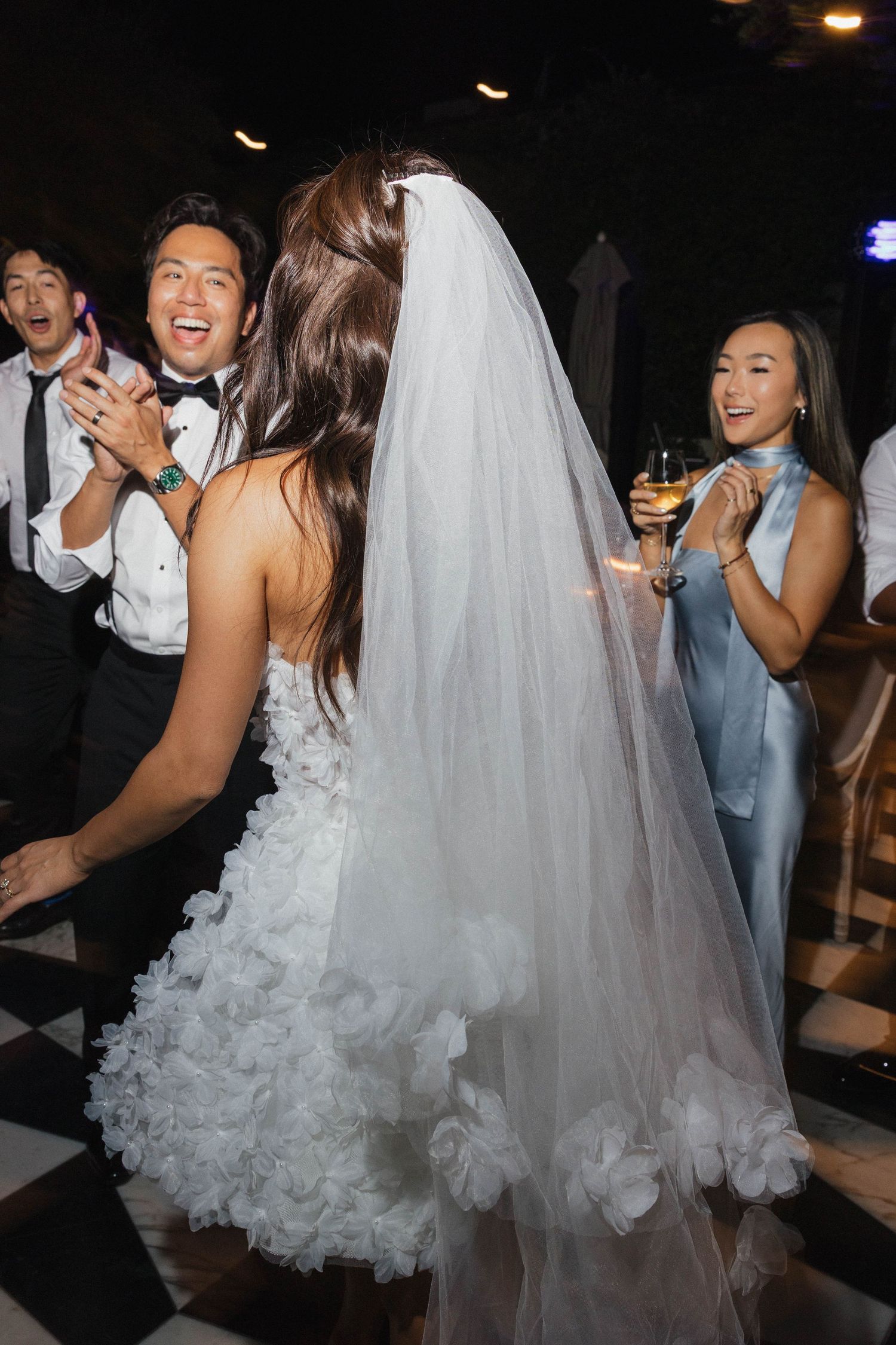 Wedding celebration on dance floor with guests in formal attire enjoying the festivities.