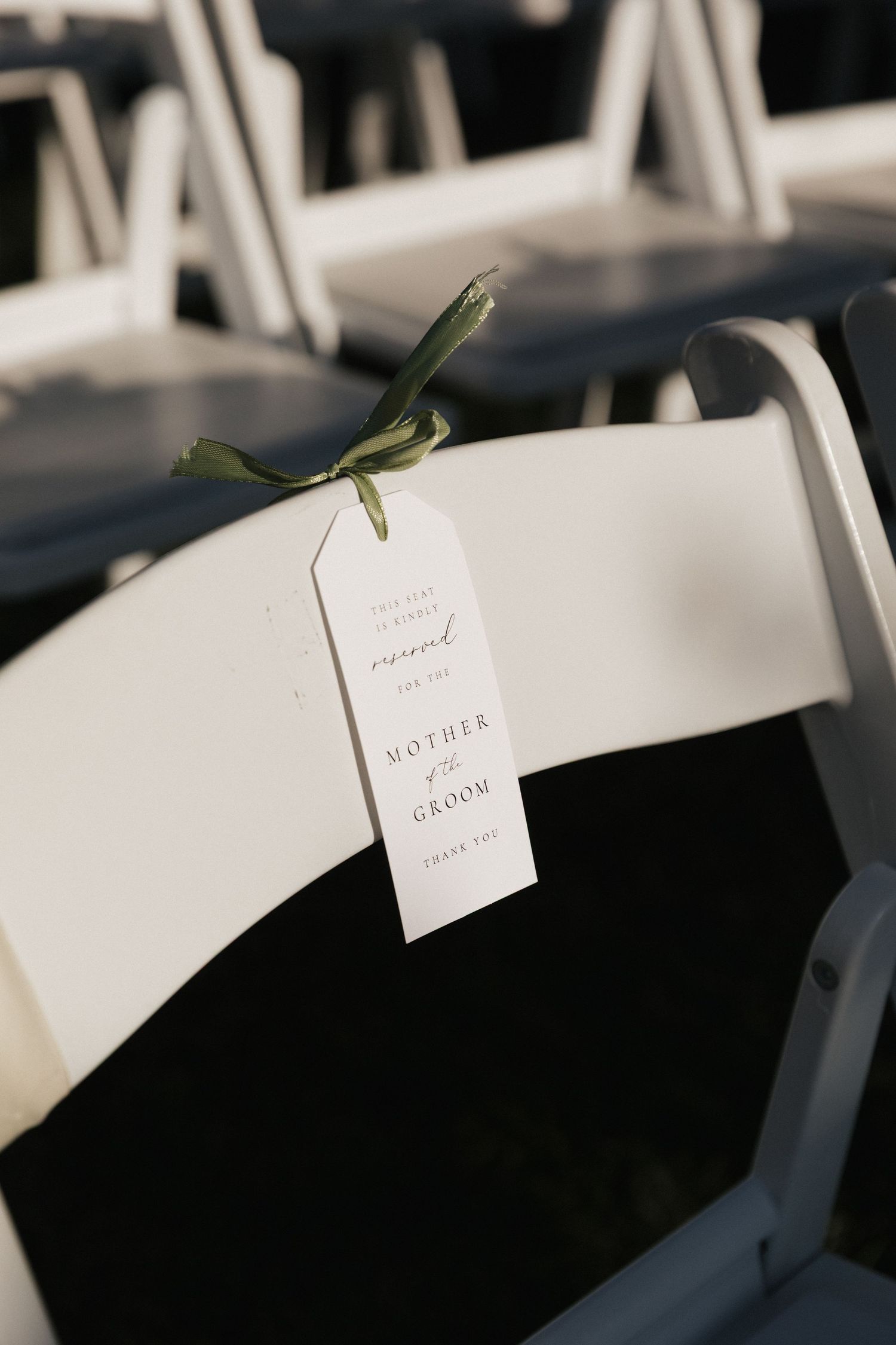 White wedding ceremony chairs with name cards attached.