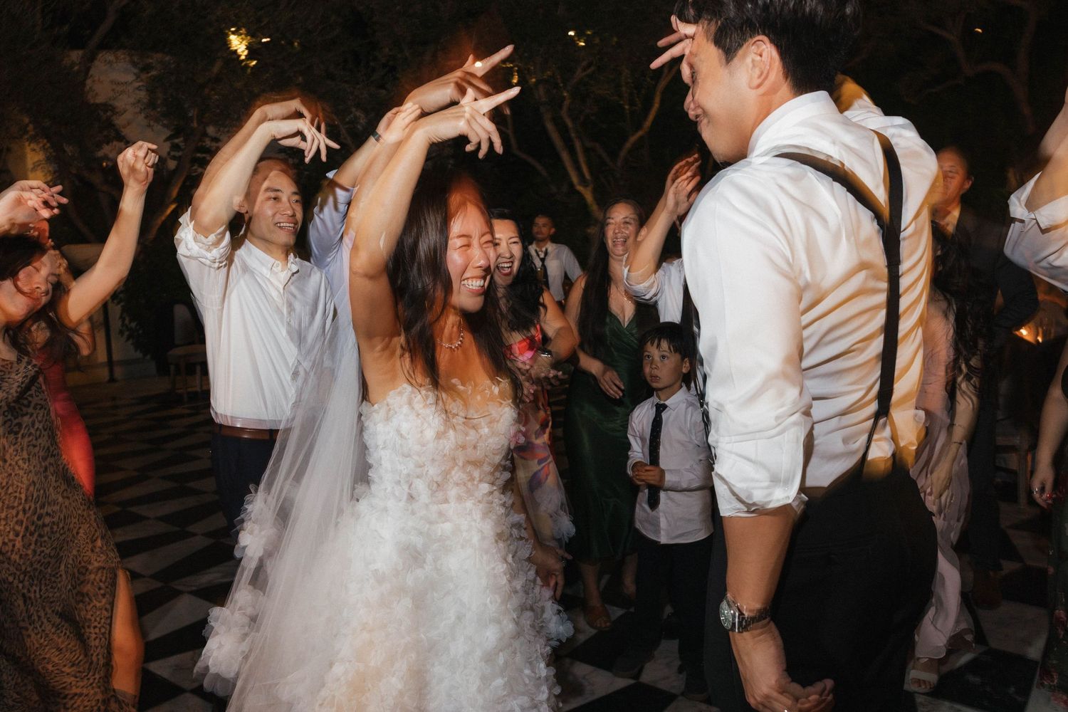 Wedding reception dance party under evening lights with guests celebrating.
