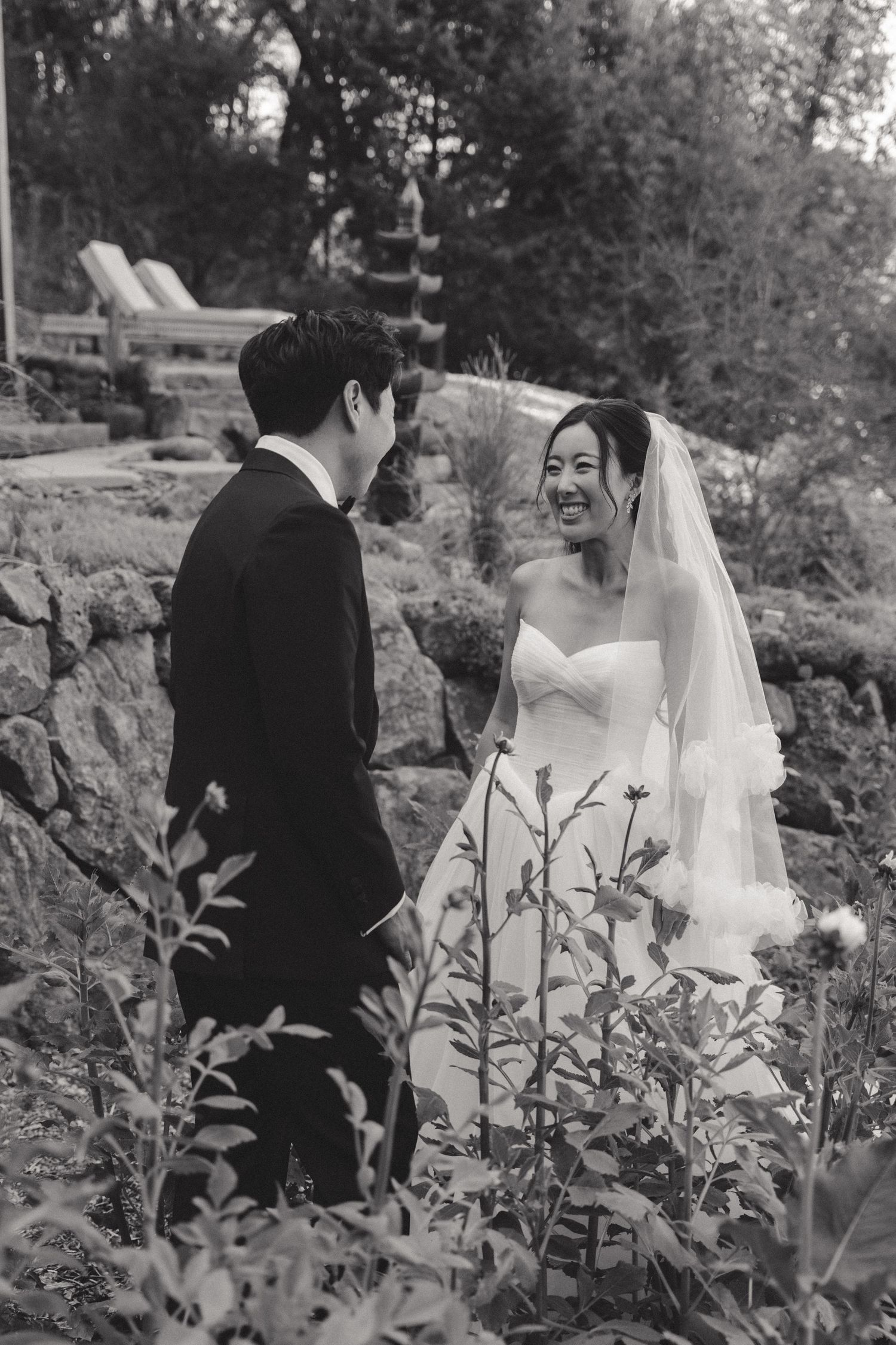 Black and white wedding photos captured in a garden setting with natural foliage.