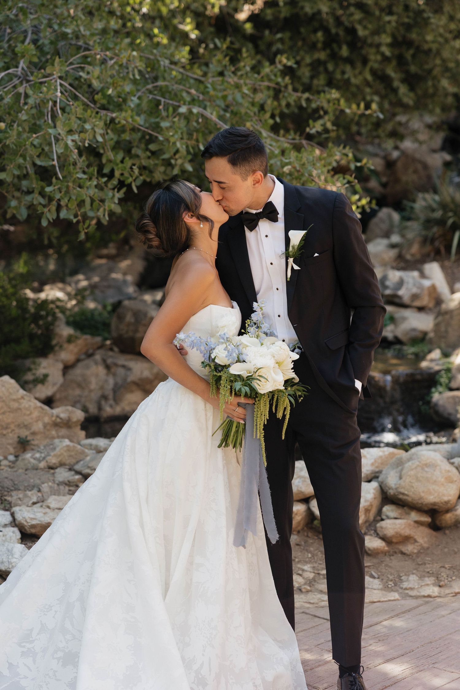Romantic wedding portraits on a stone path surrounded by natural greenery.