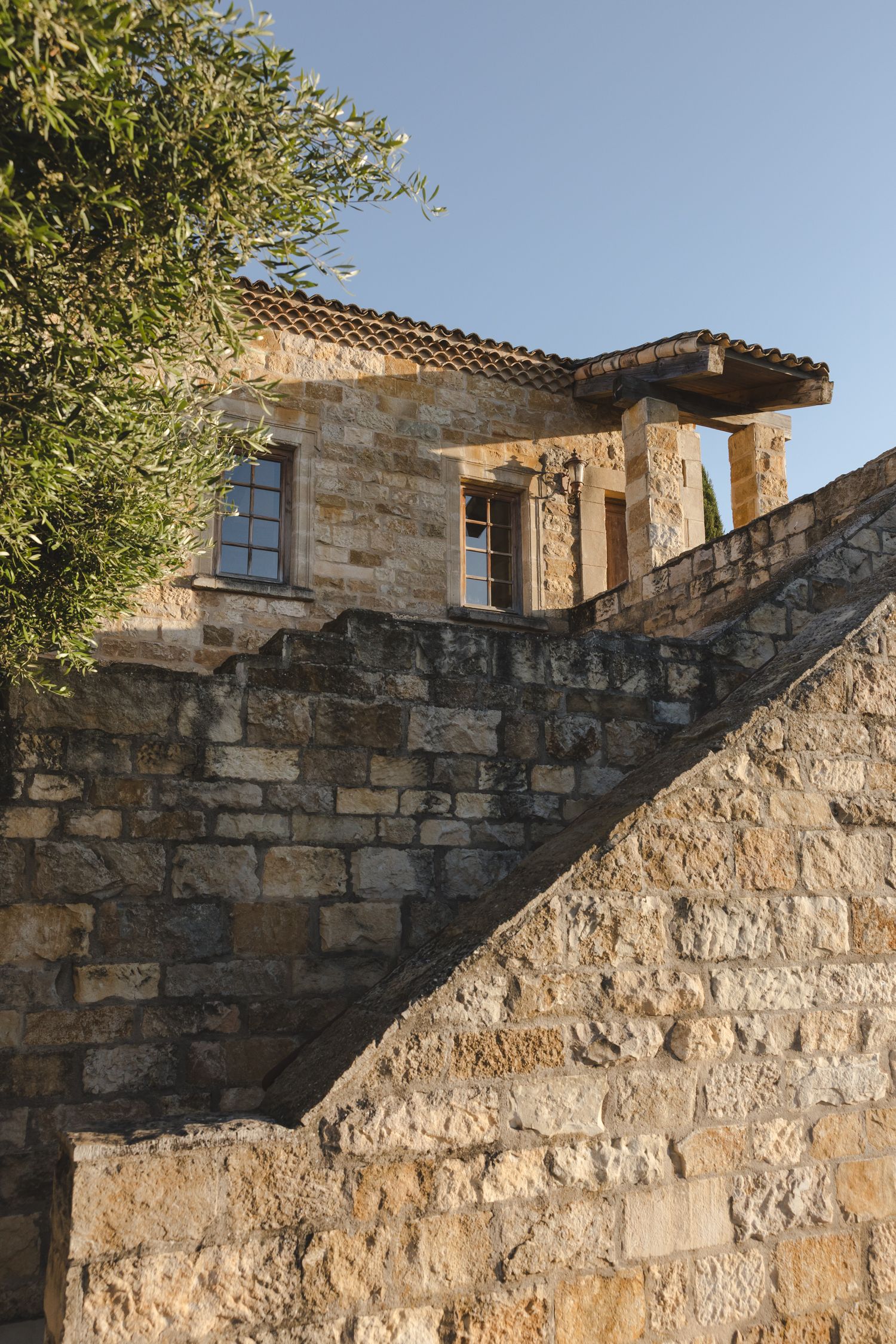 Historic stone building exterior with rustic architectural details and terracotta roof tiles.