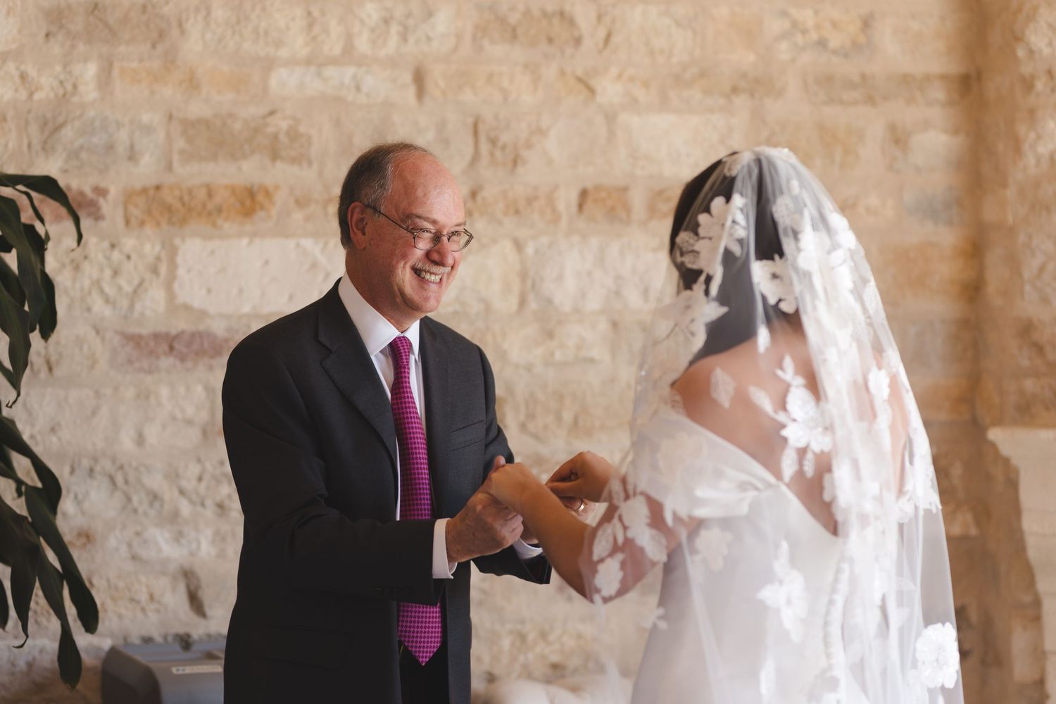 Emotional moment shared during wedding ceremony in stone-walled venue.