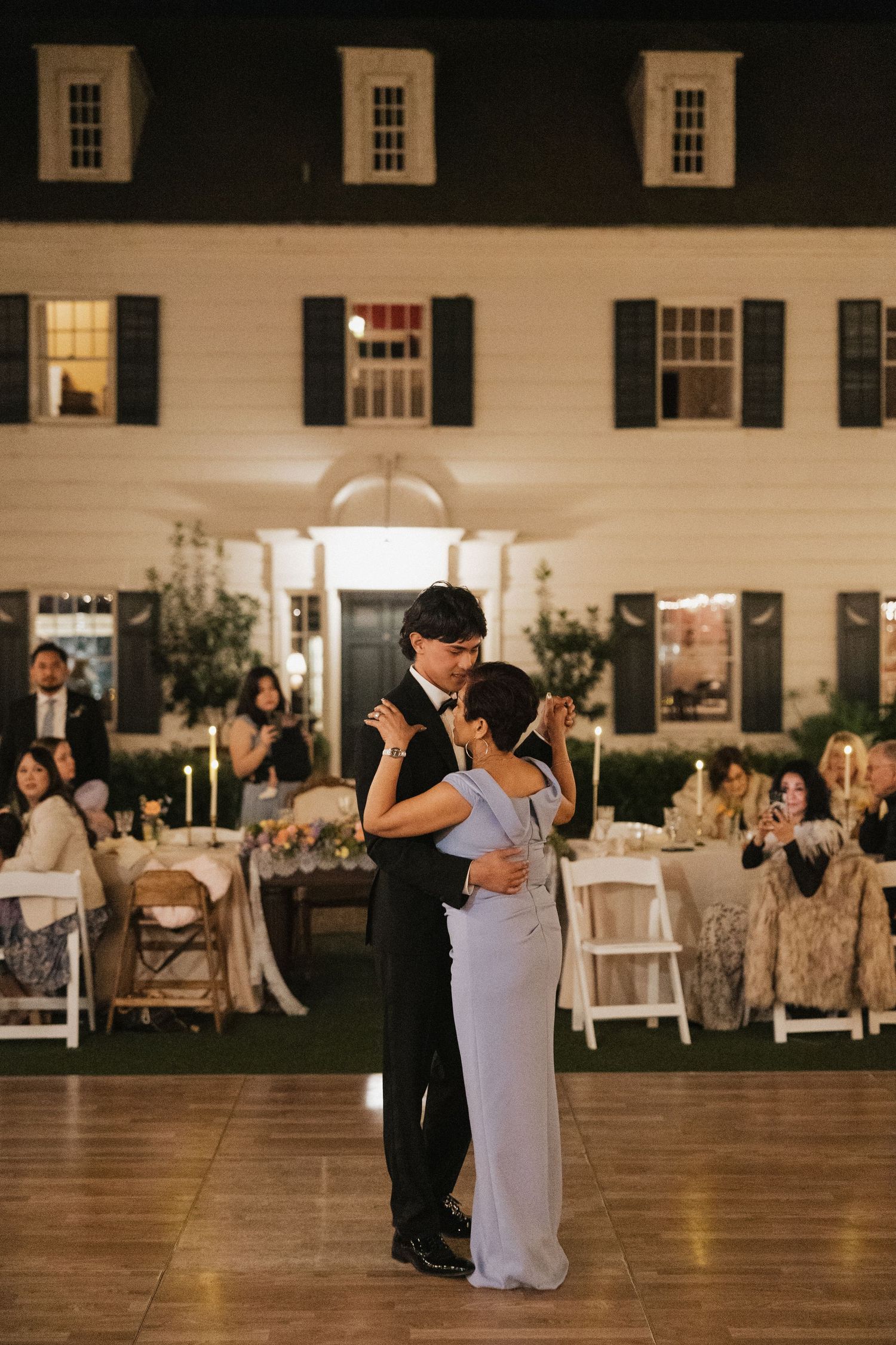 Wedding reception first dance in an elegant white barn venue with string lights.
