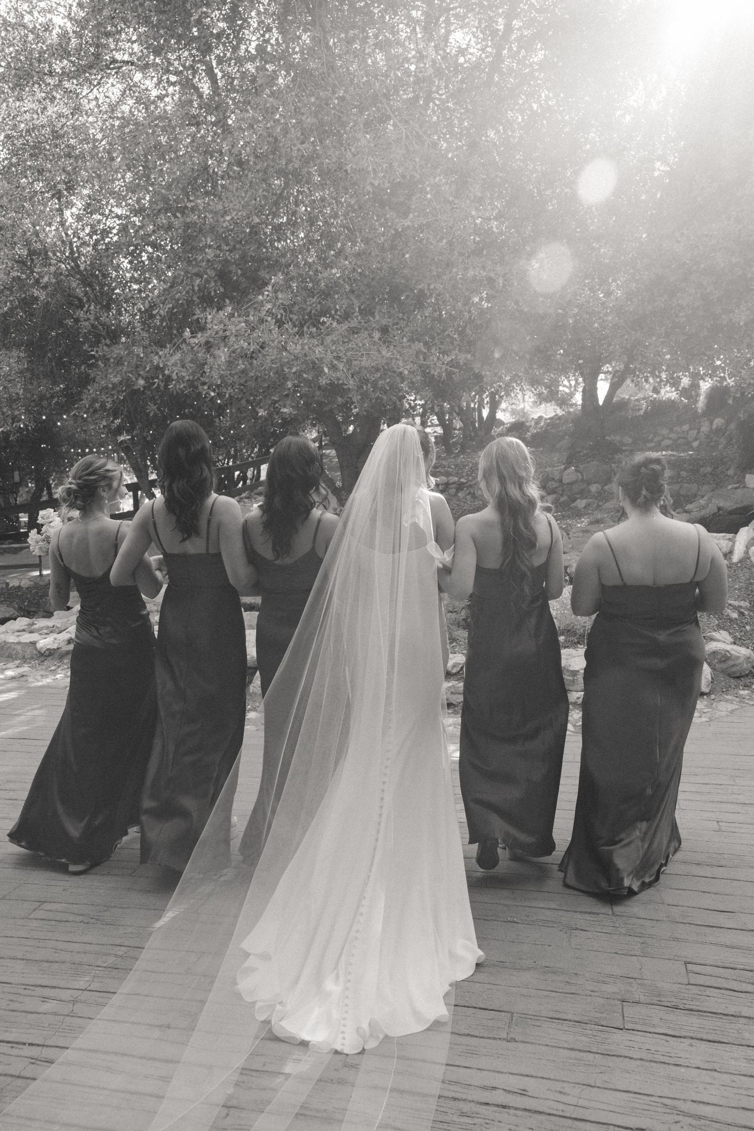 Wedding ceremony guests seated outdoors on a wooden deck at sunset.