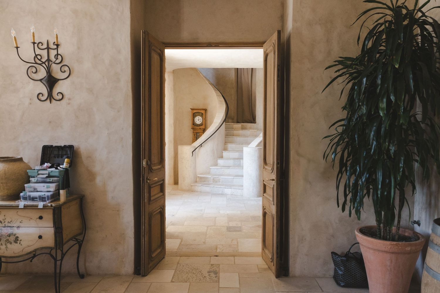 Interior hallway of a Mediterranean-style building with arched doorways and potted plants.