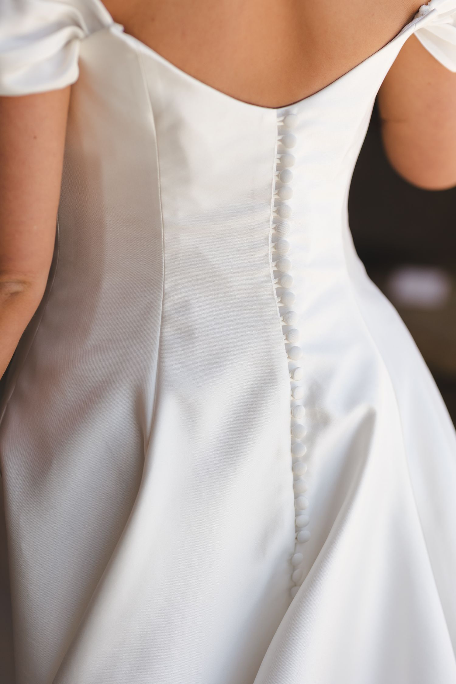 Detail shot of white wedding dress buttons and seams along the back.