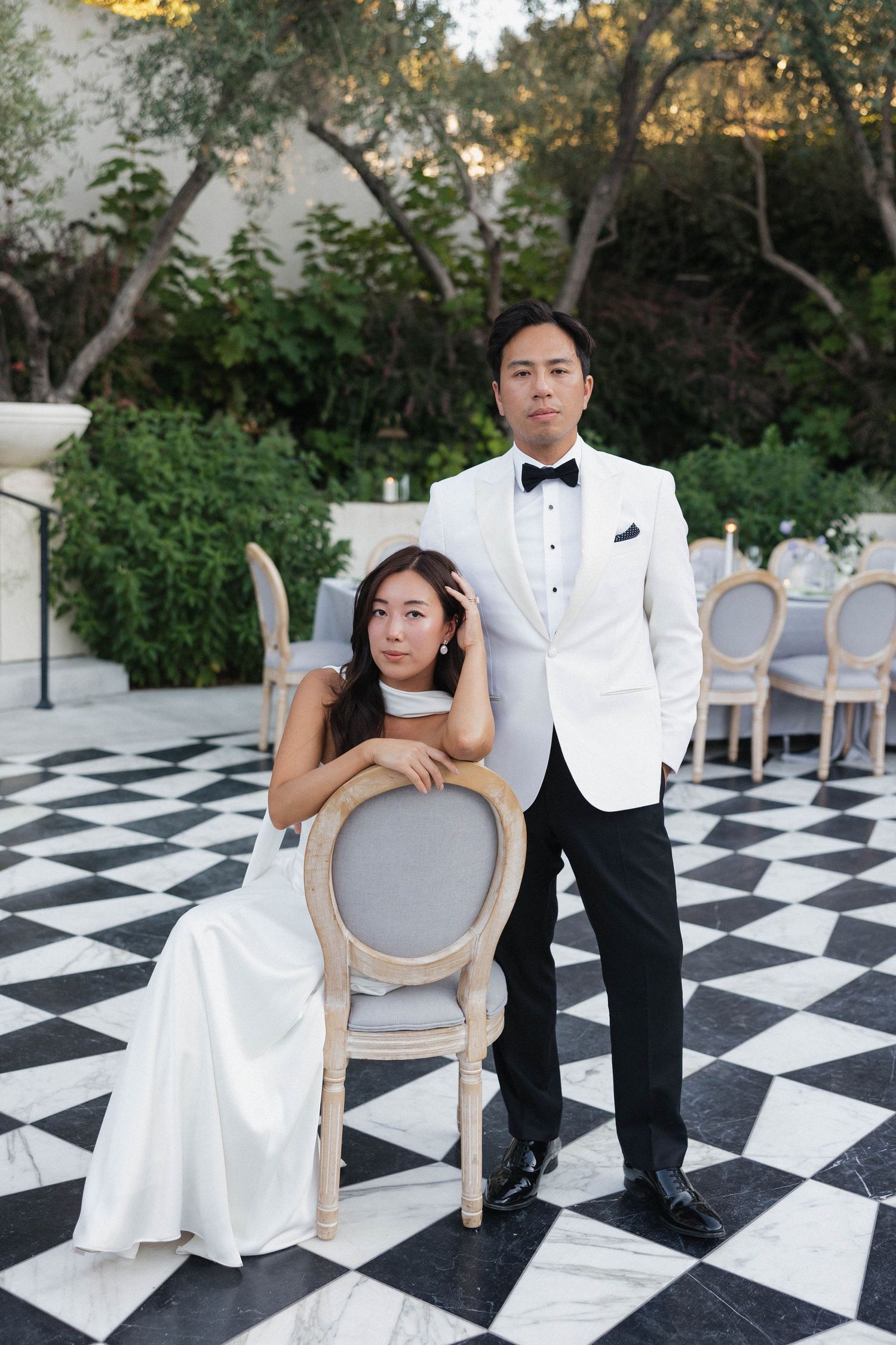 Elegant wedding portraits on a geometric black and white patterned floor with vintage chairs.