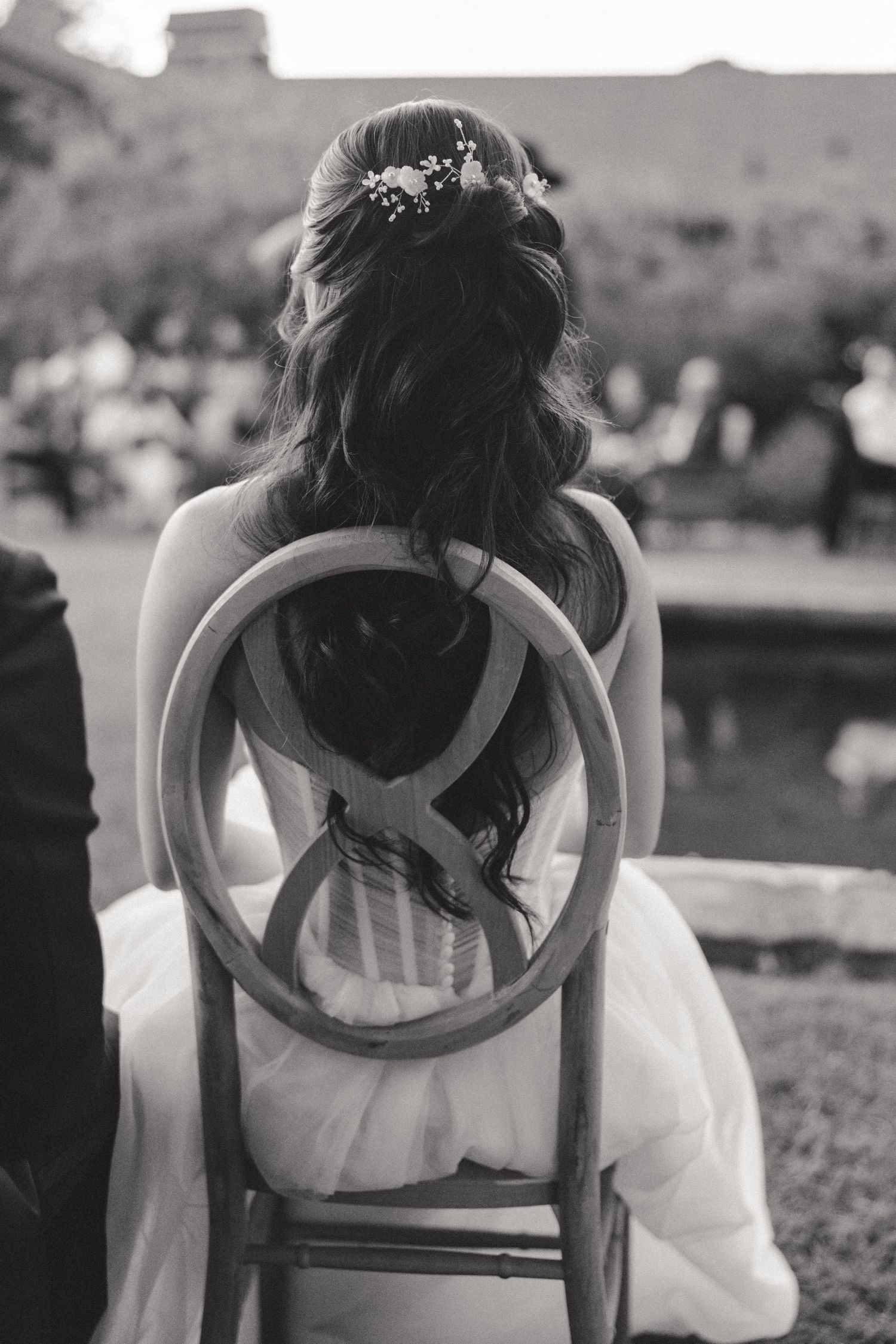 A row of vintage wooden chairs set up for an outdoor wedding ceremony.