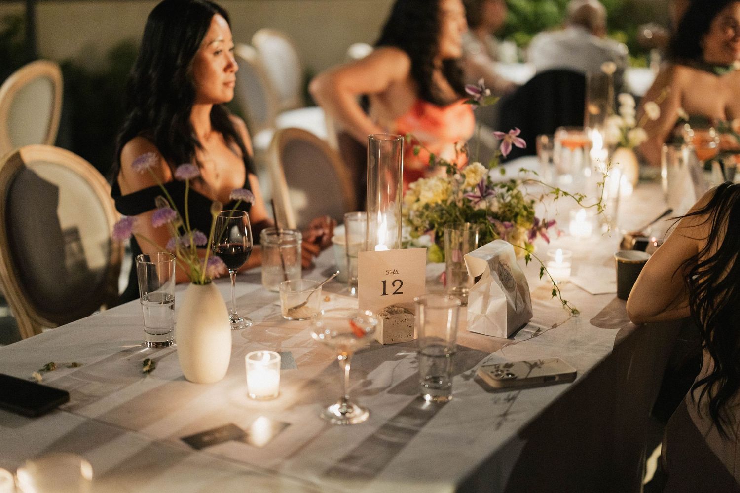 Intimate wedding reception table settings with glowing candles and white floral centerpieces.