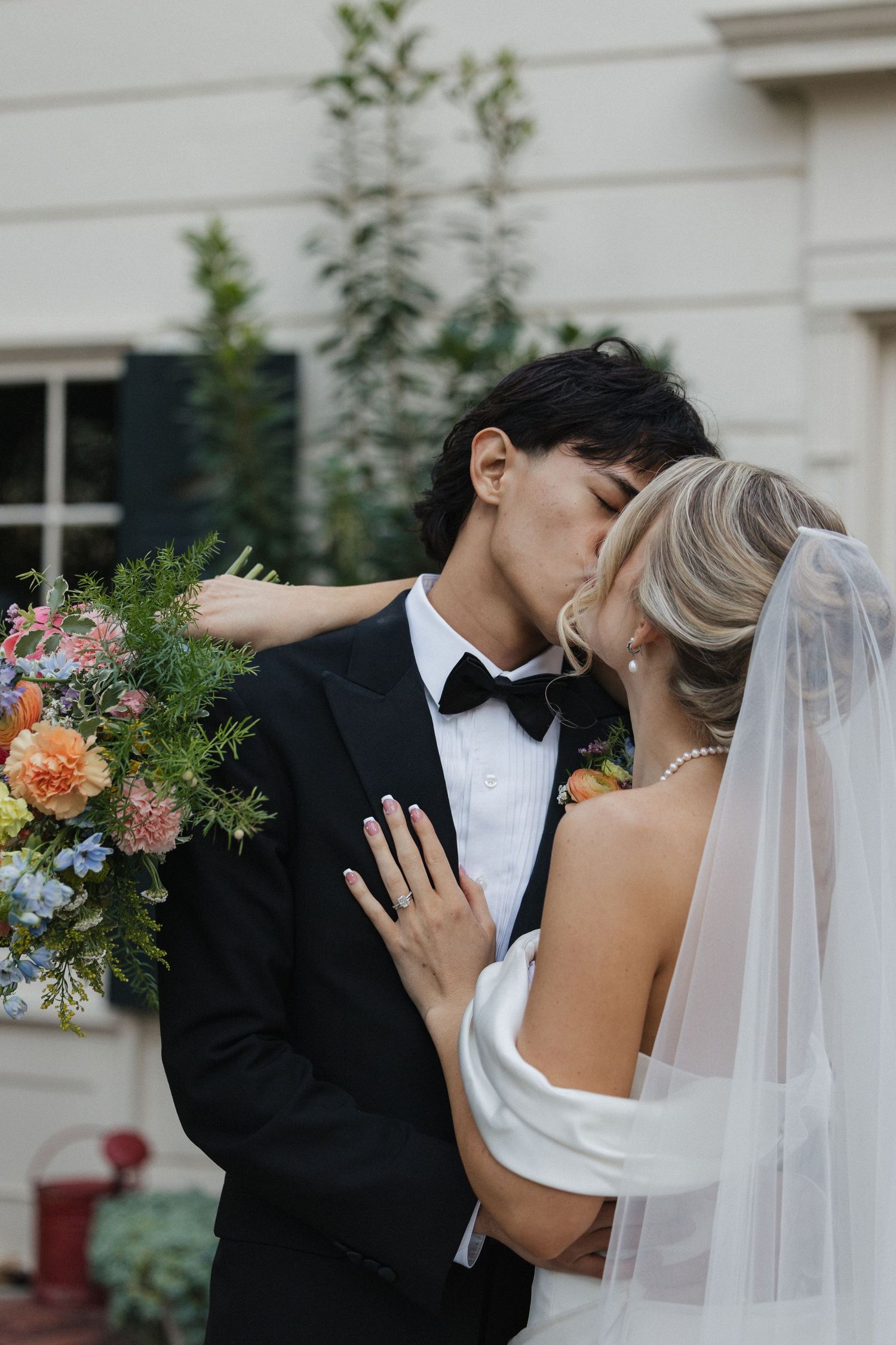Romantic wedding portraits with bride in flowing veil and groom in classic tuxedo.