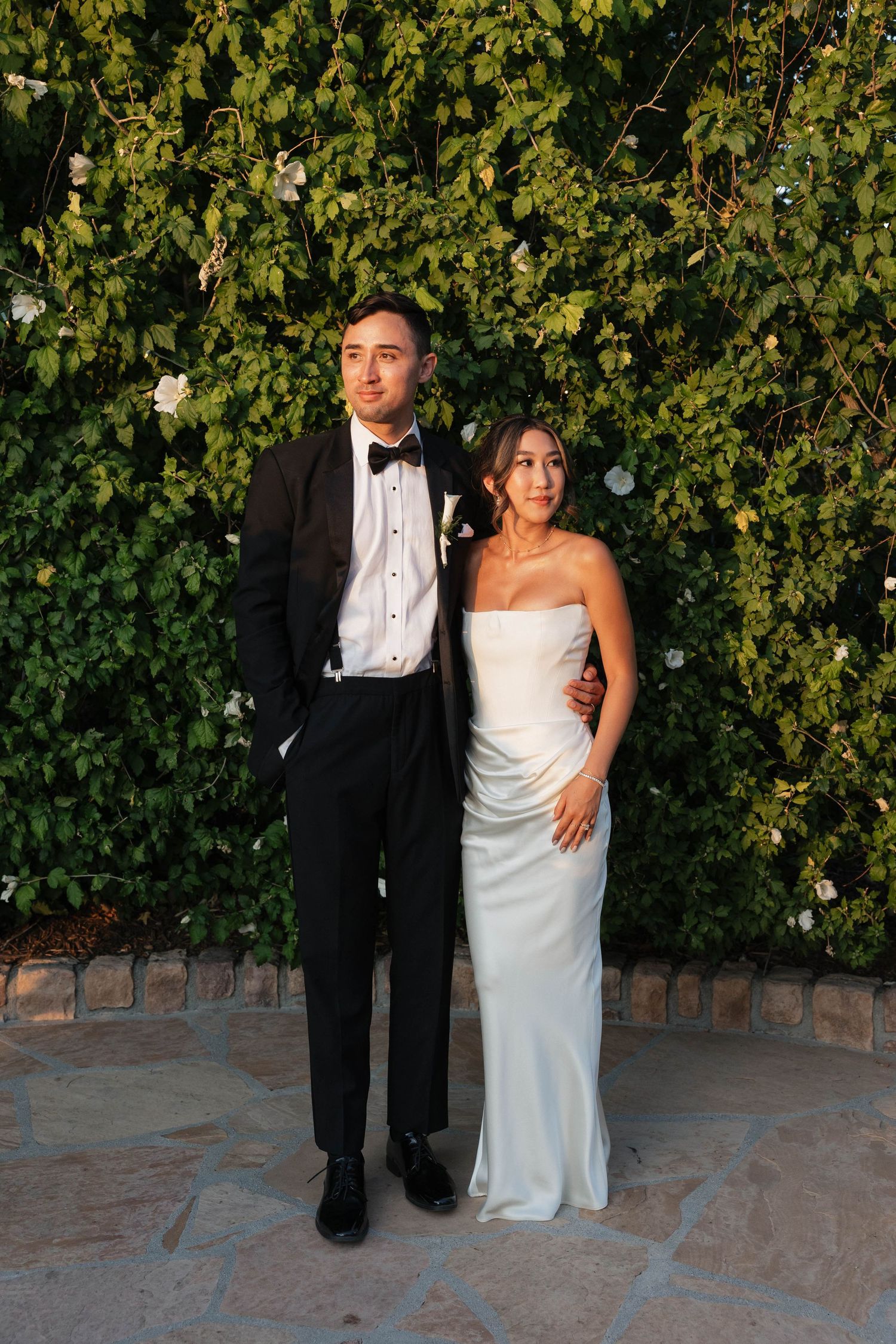Formal wedding portrait against lush green vine wall backdrop.