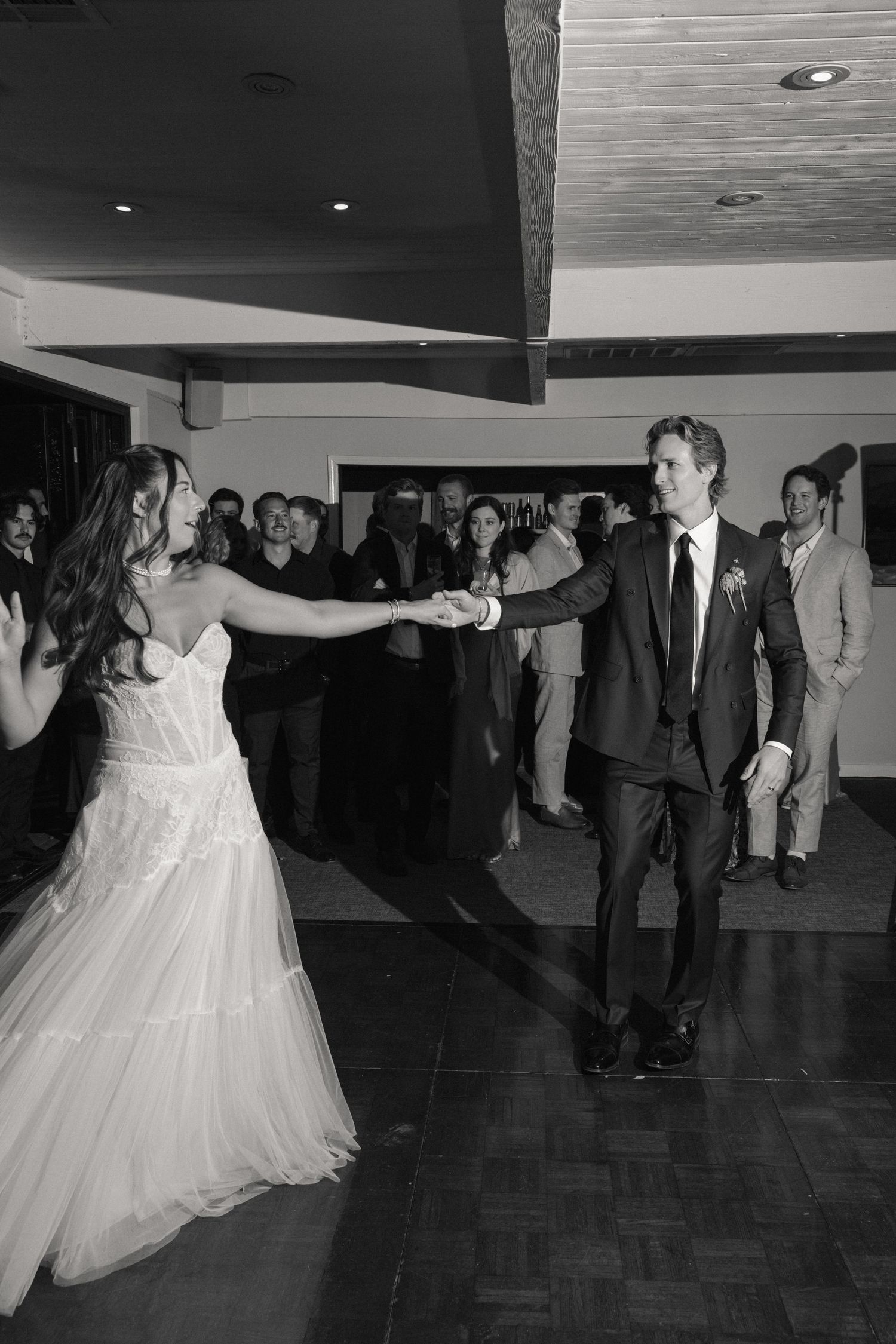 Bride and groom share a joyful first dance surrounded by guests at their wedding reception.
