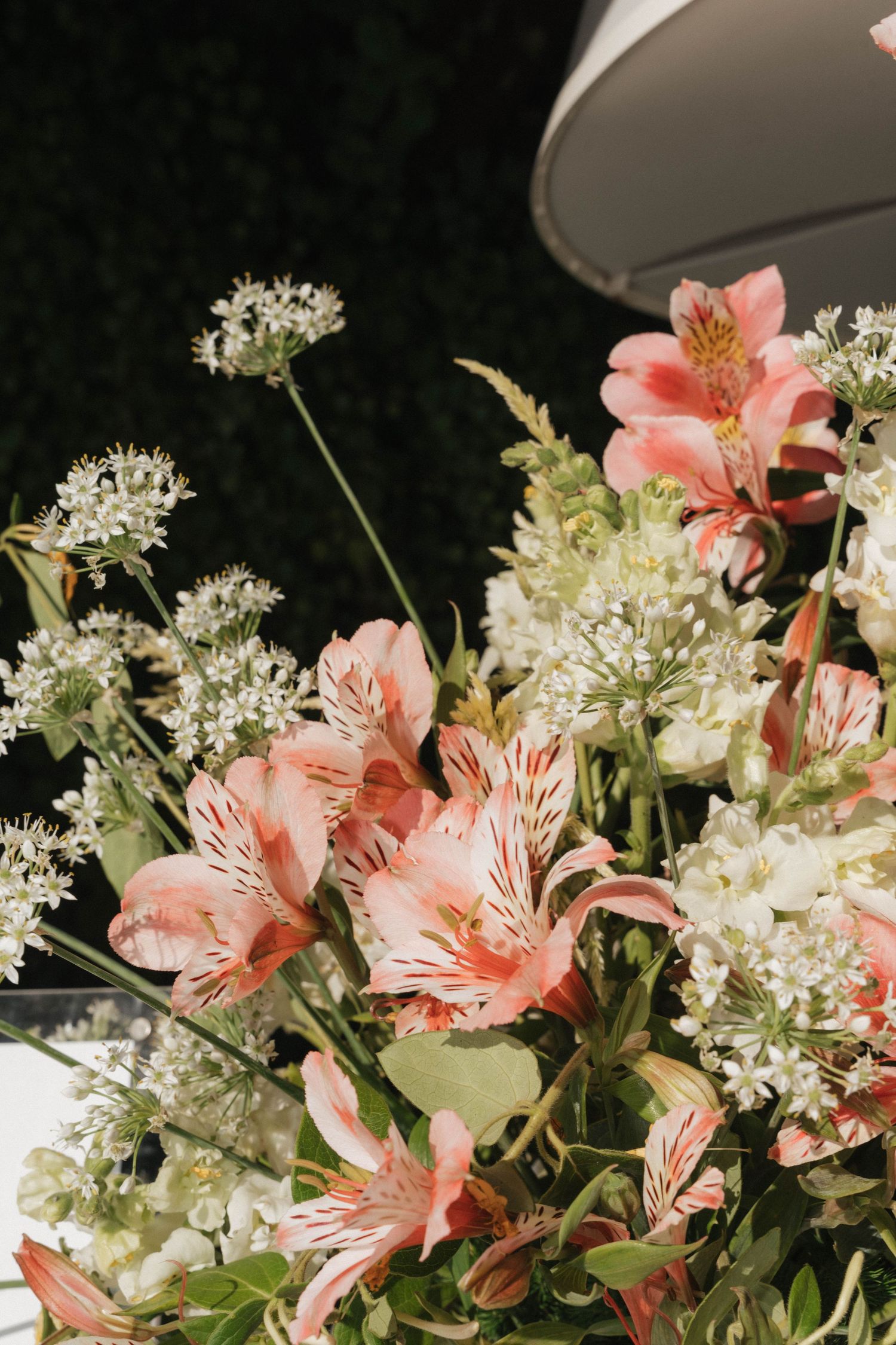 Delicate pink and white floral arrangement with alstroemeria and baby's breath against dark background.