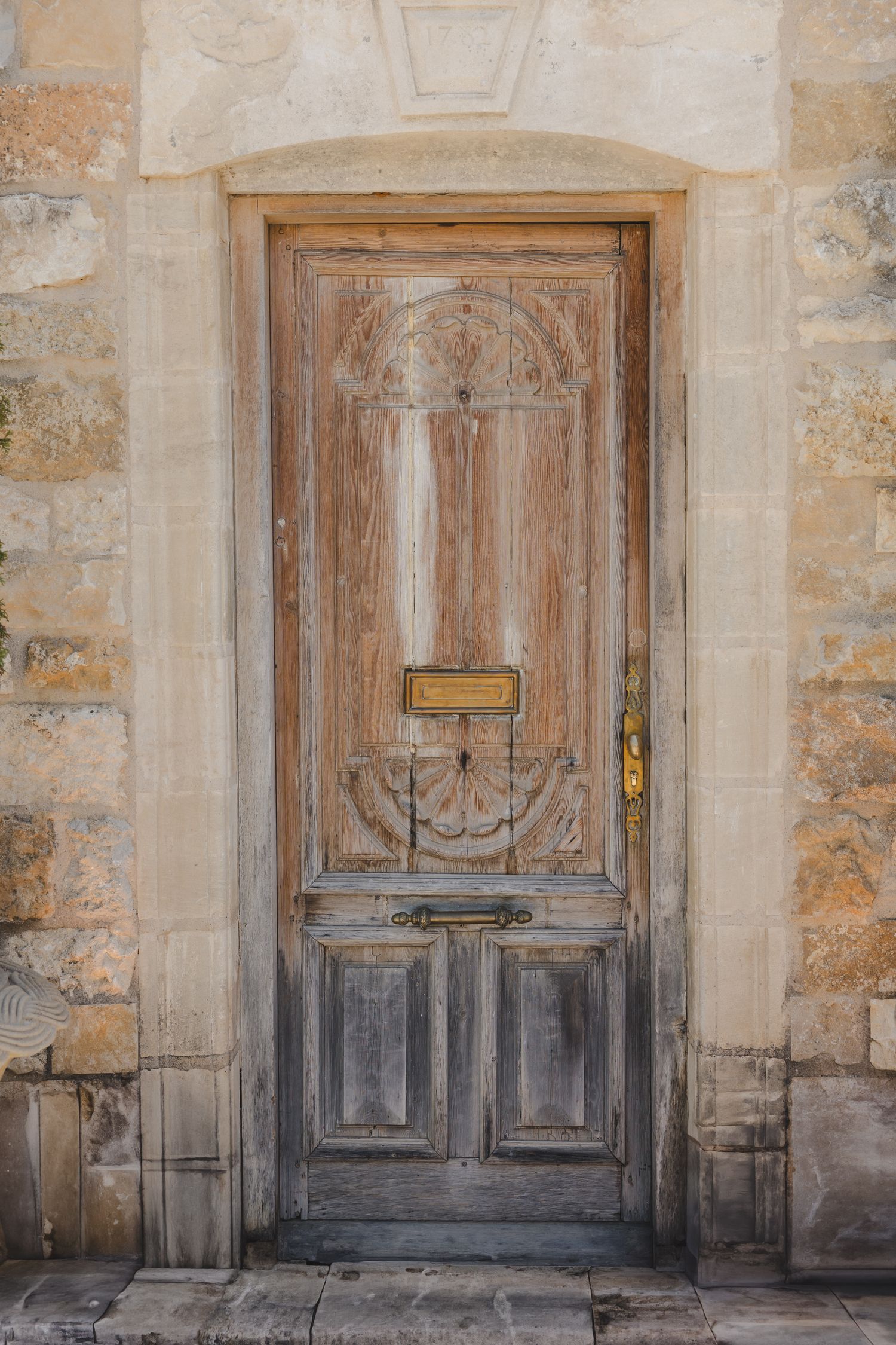 Weathered wooden doors with ornate panels against stone wall architecture.